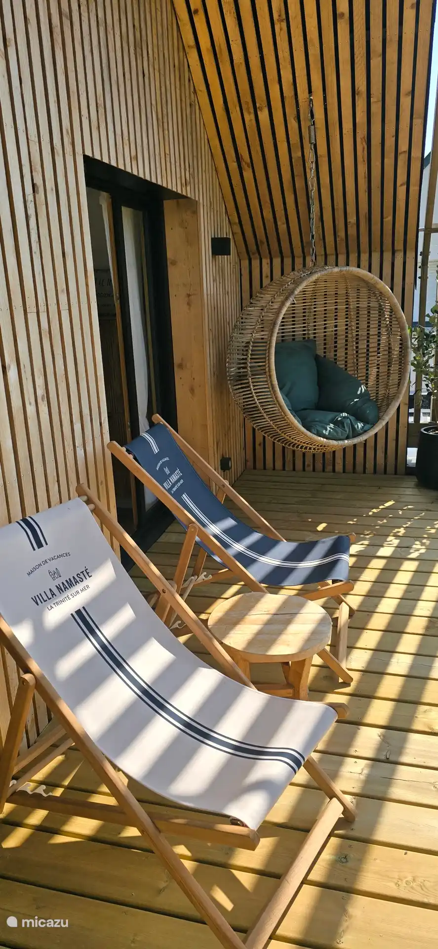 Terrasse bois avec chiliennes et fauteuil suspendu, idéale pour se détendre à l’ombre et profiter d’un moment de calme en toute sérénité.