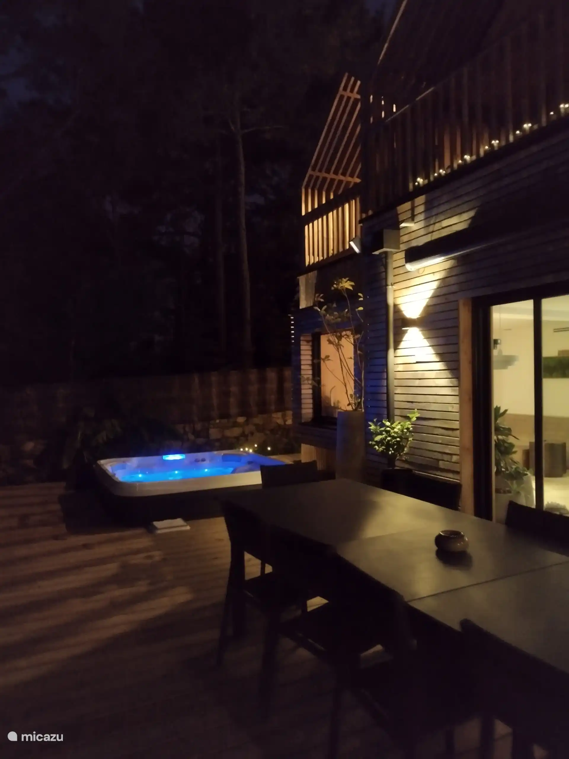 Terrasse de nuit avec spa éclairé, offrant une ambiance chaleureuse et relaxante pour profiter de moments de détente en extérieur.