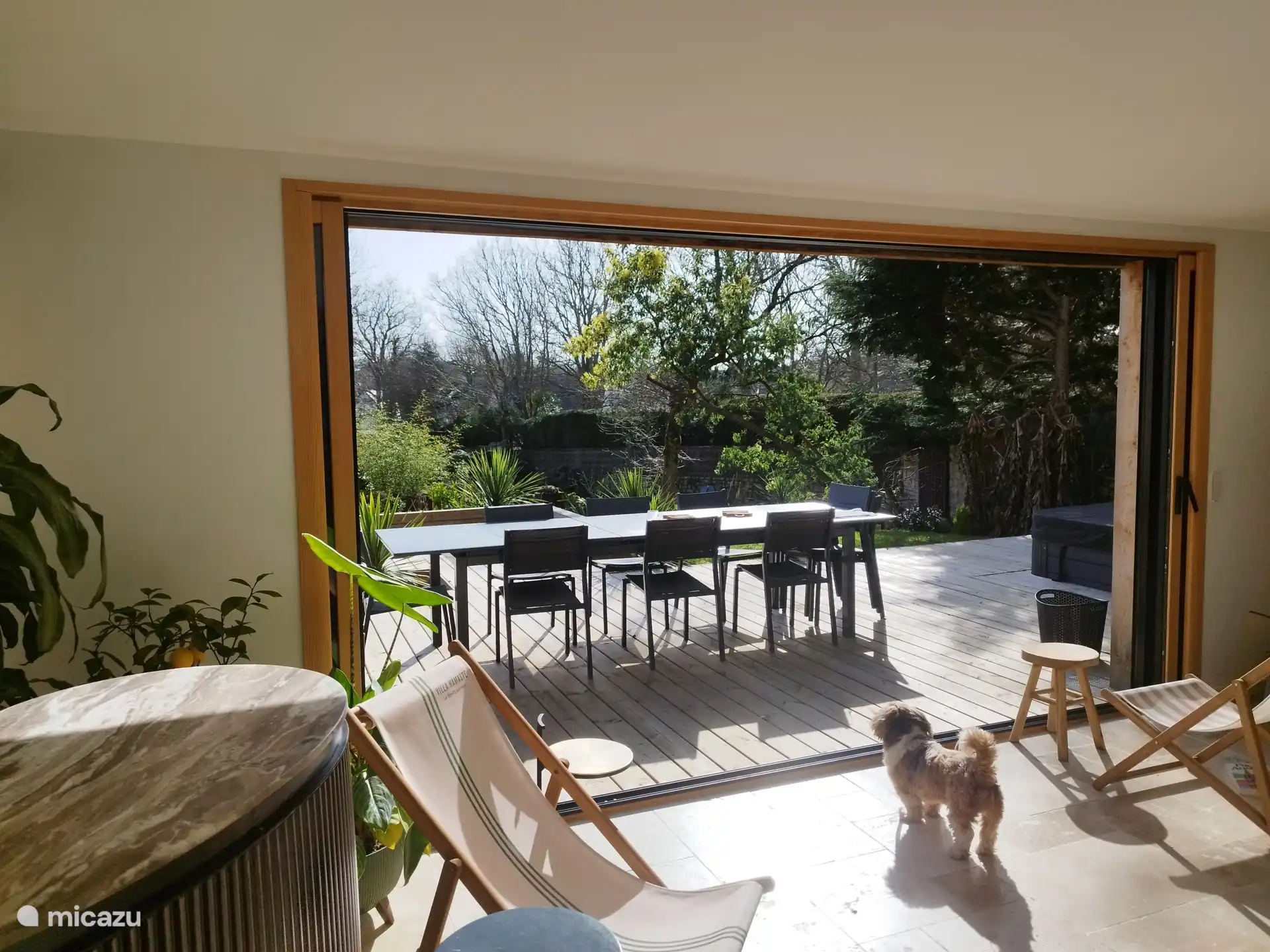 Vue sur la terrasse depuis l’intérieur, offrant une belle ouverture sur l’extérieur et un accès direct à l’espace repas et détente.