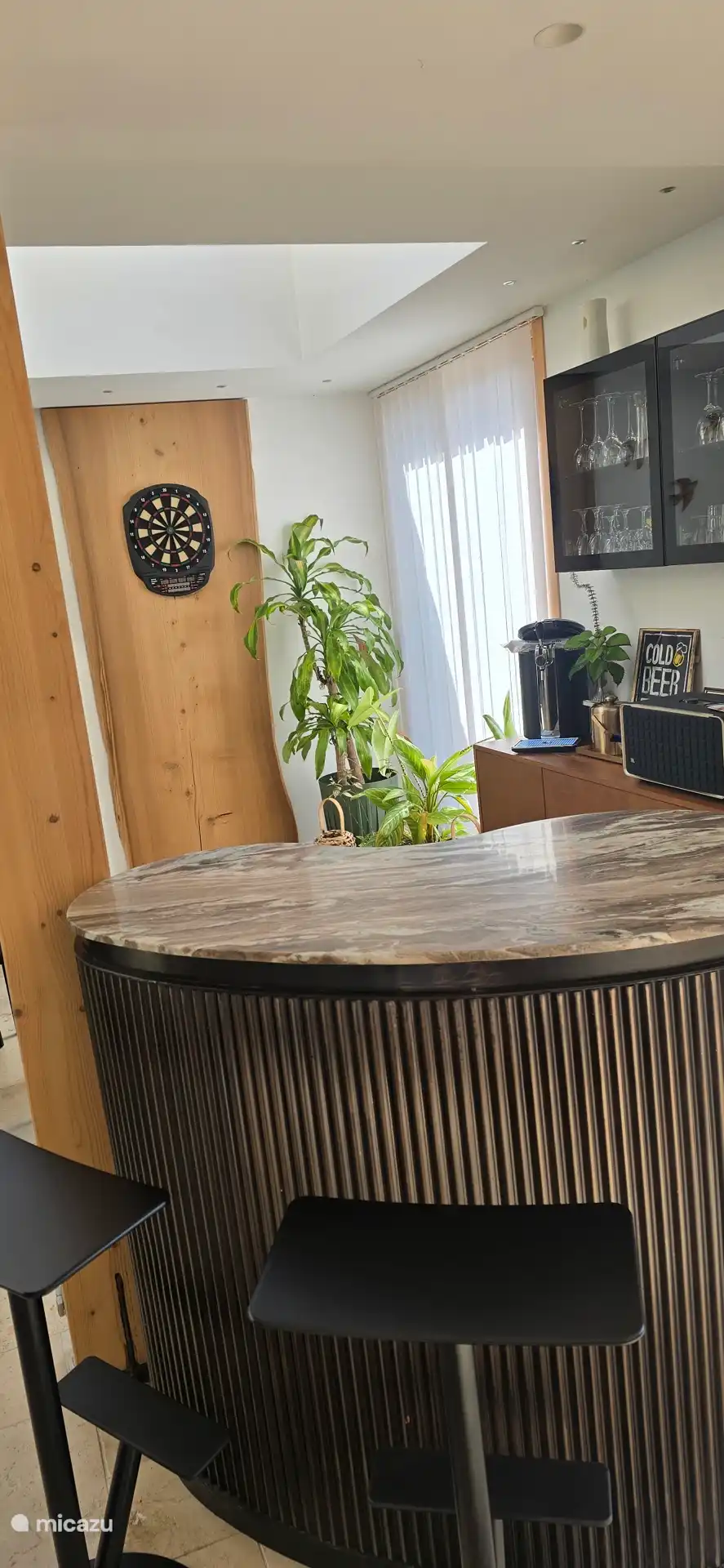 Espace bar convivial avec comptoir et fléchettes électroniques, idéal pour partager un moment autour d’un verre ou d’un café dans une ambiance chaleureuse.