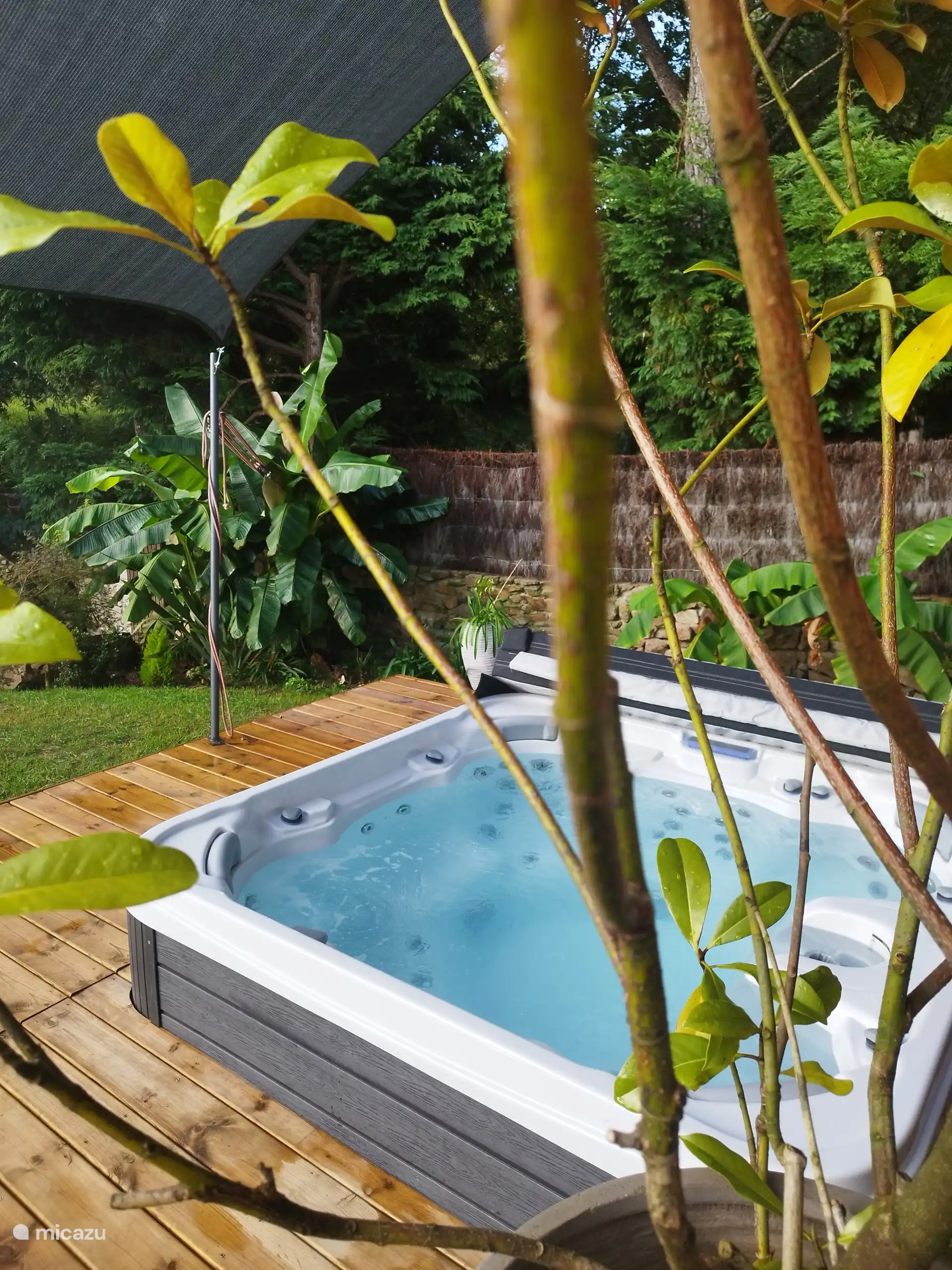 Spa extérieur 7 places entouré de végétation, espace intime et apaisant pour se détendre en toute tranquillité. Installé sur la terrasse, il invite à profiter pleinement de moments de relaxation.