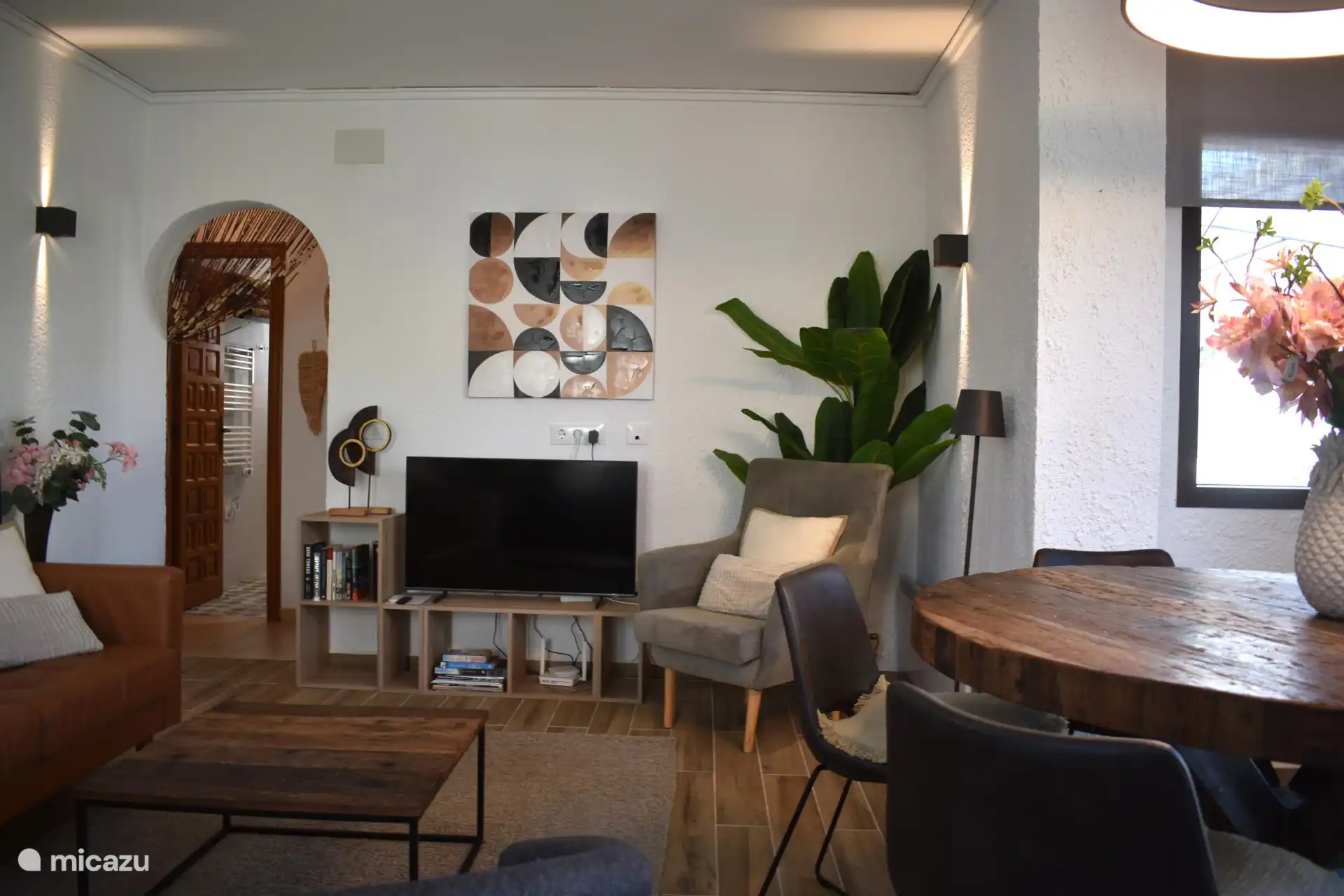 Een gezellig ingerichte woonkamer met TV, zithoek en eettafel.