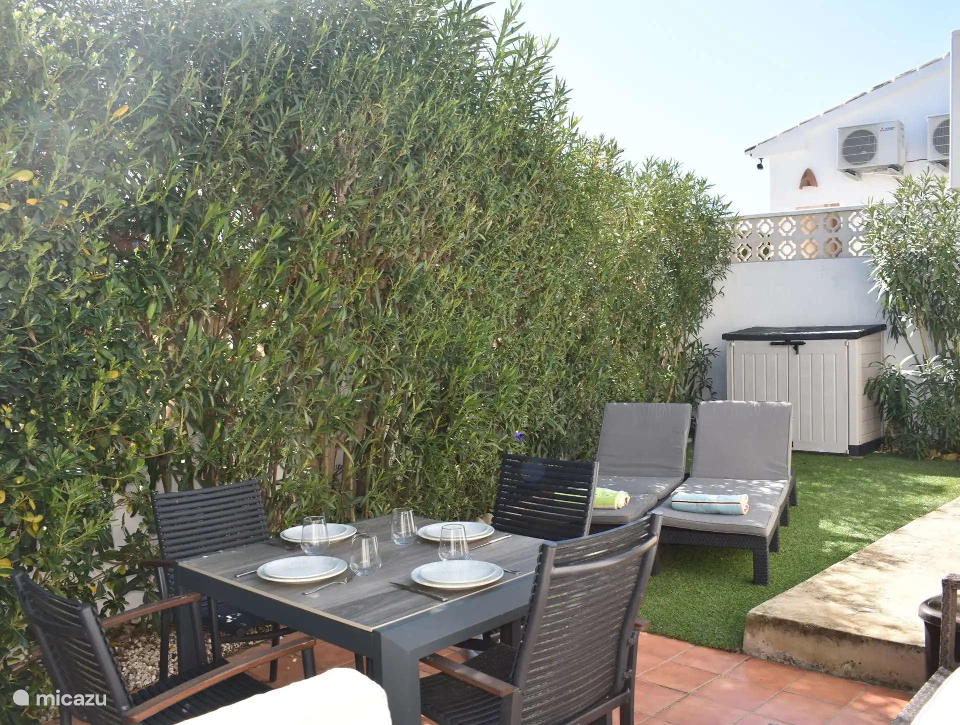 Ook aan de achterzijde van het huis is nog een kleine tuin met 2 fijne ligstoelen en een eettafel om in de schaduw te kunnen ontbijten.
