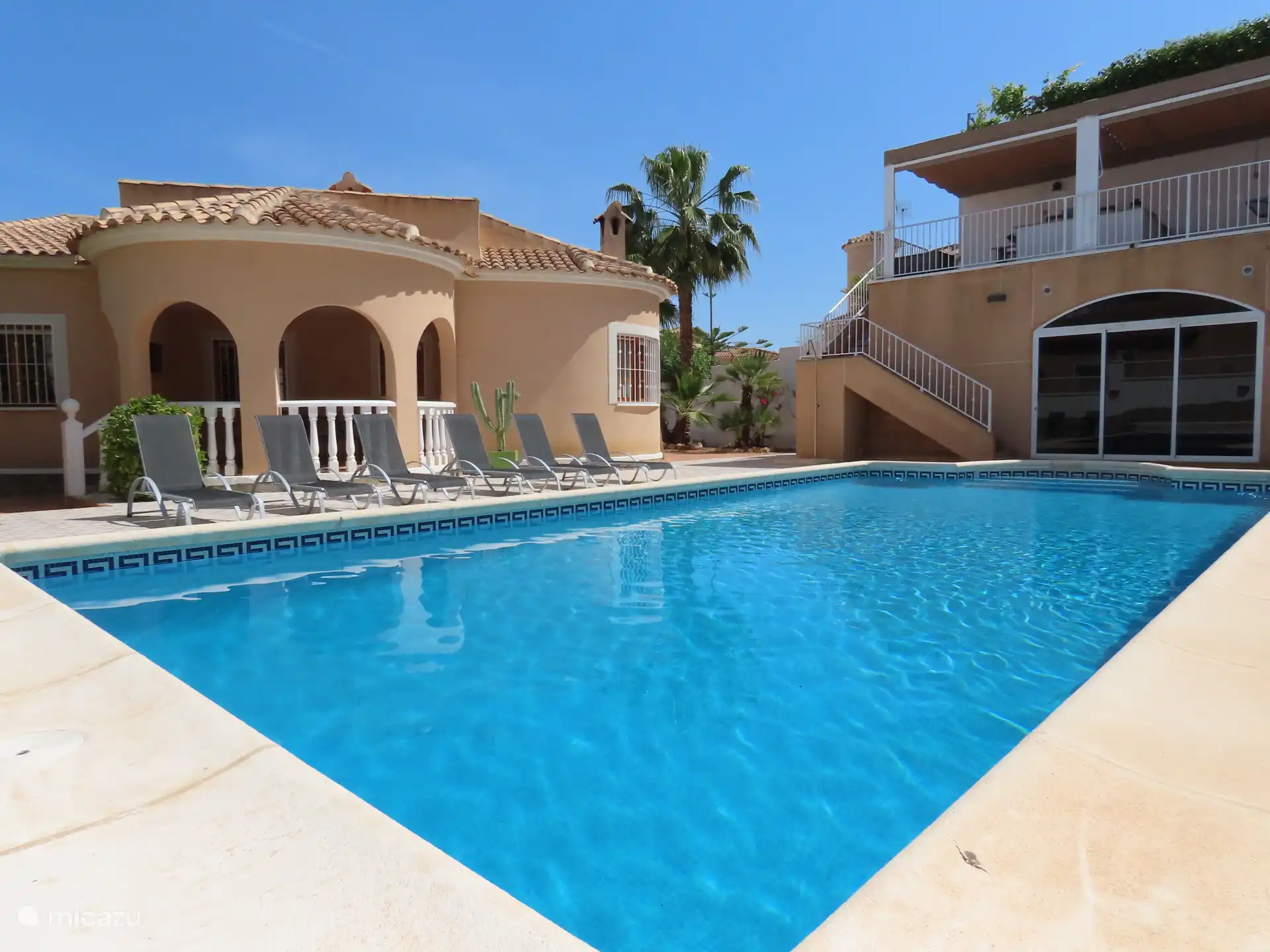 Terras, zwembad en afgesloten ruimte (glazen pui) met daarboven zitgelegenheid en de buitenkeuken.