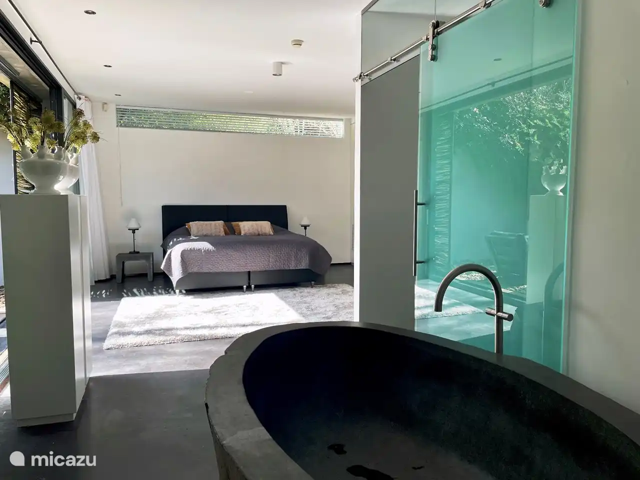 Bedroom with natural stone bath and access to terrace with outdoor pool and hot tub