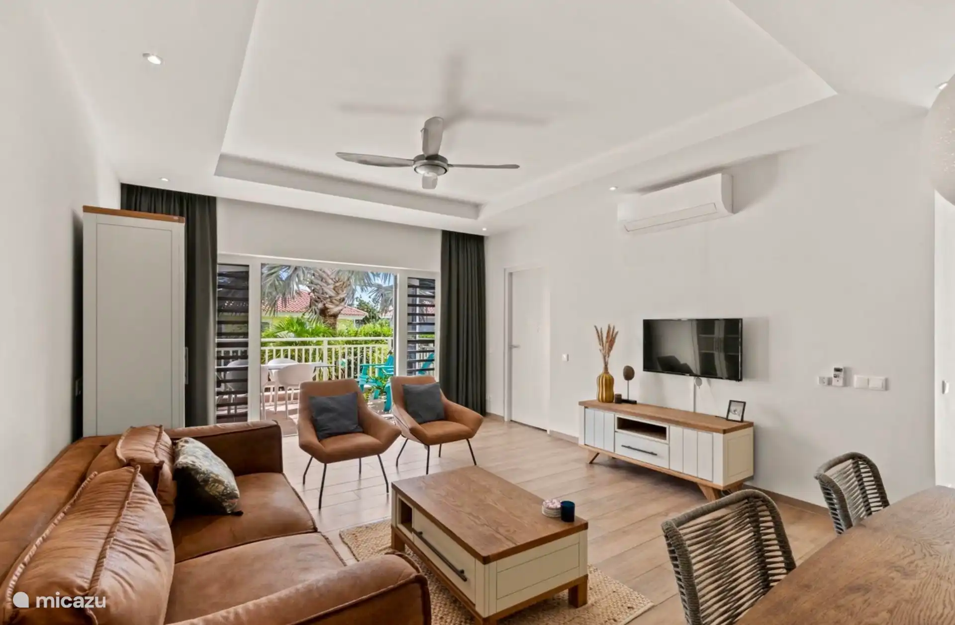 Un salón espacioso y encantador con puertas de patio que dan a la terraza con vistas al jardín tropical y mucha privacidad.