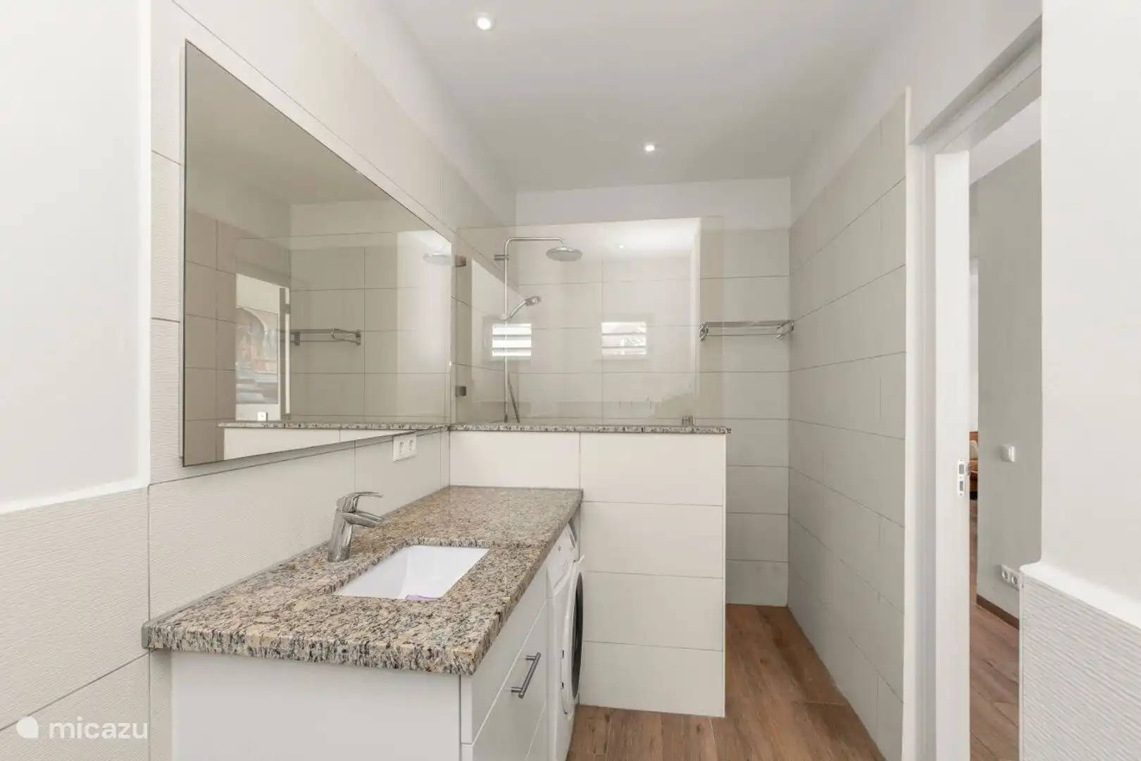 Baño agradable con ducha a las camas de cama natural, lavabo, inodoro y lavadora.