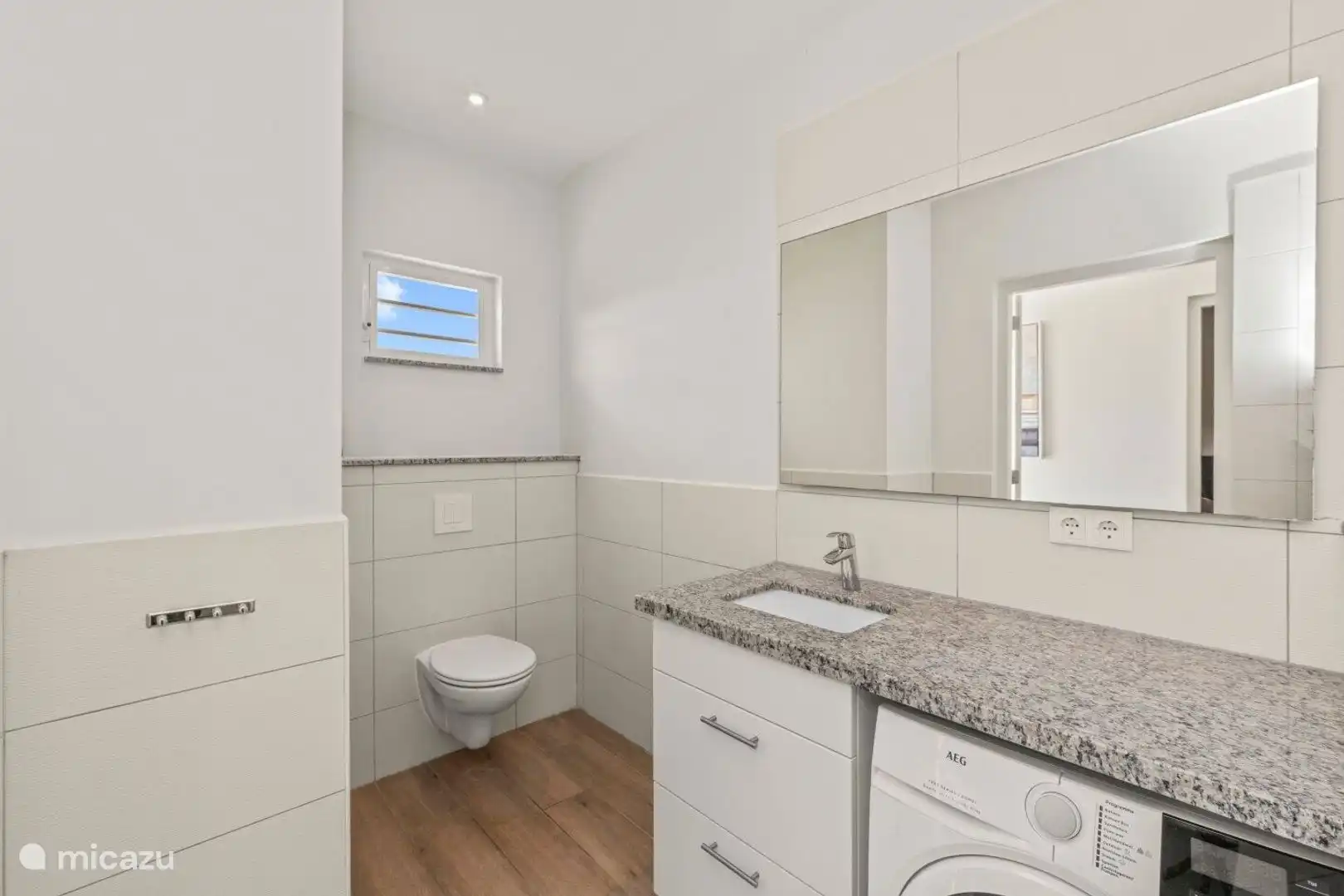 Baño agradable con ducha a las camas de cama natural, lavabo, inodoro y lavadora.