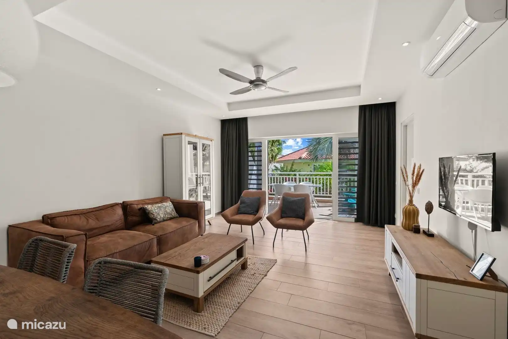 Un salón espacioso y encantador con puertas de patio que dan a la terraza con vistas al jardín tropical y mucha privacidad.