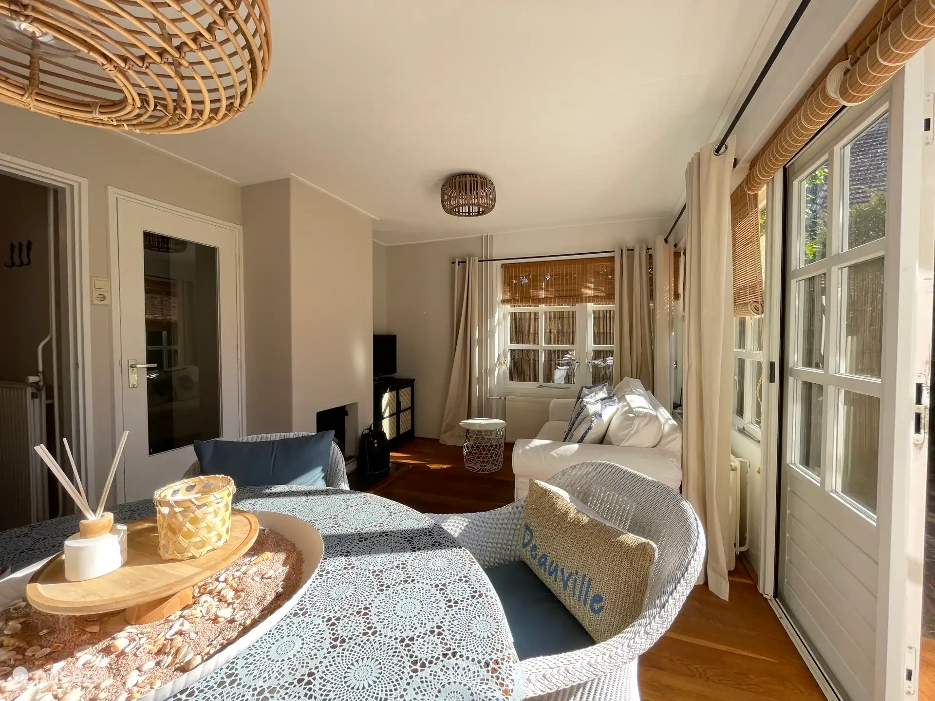 Helles Wohnzimmer, ausgestattet mit Esstisch, Sitzecke, Fernseher und gemütlichem Kamin.