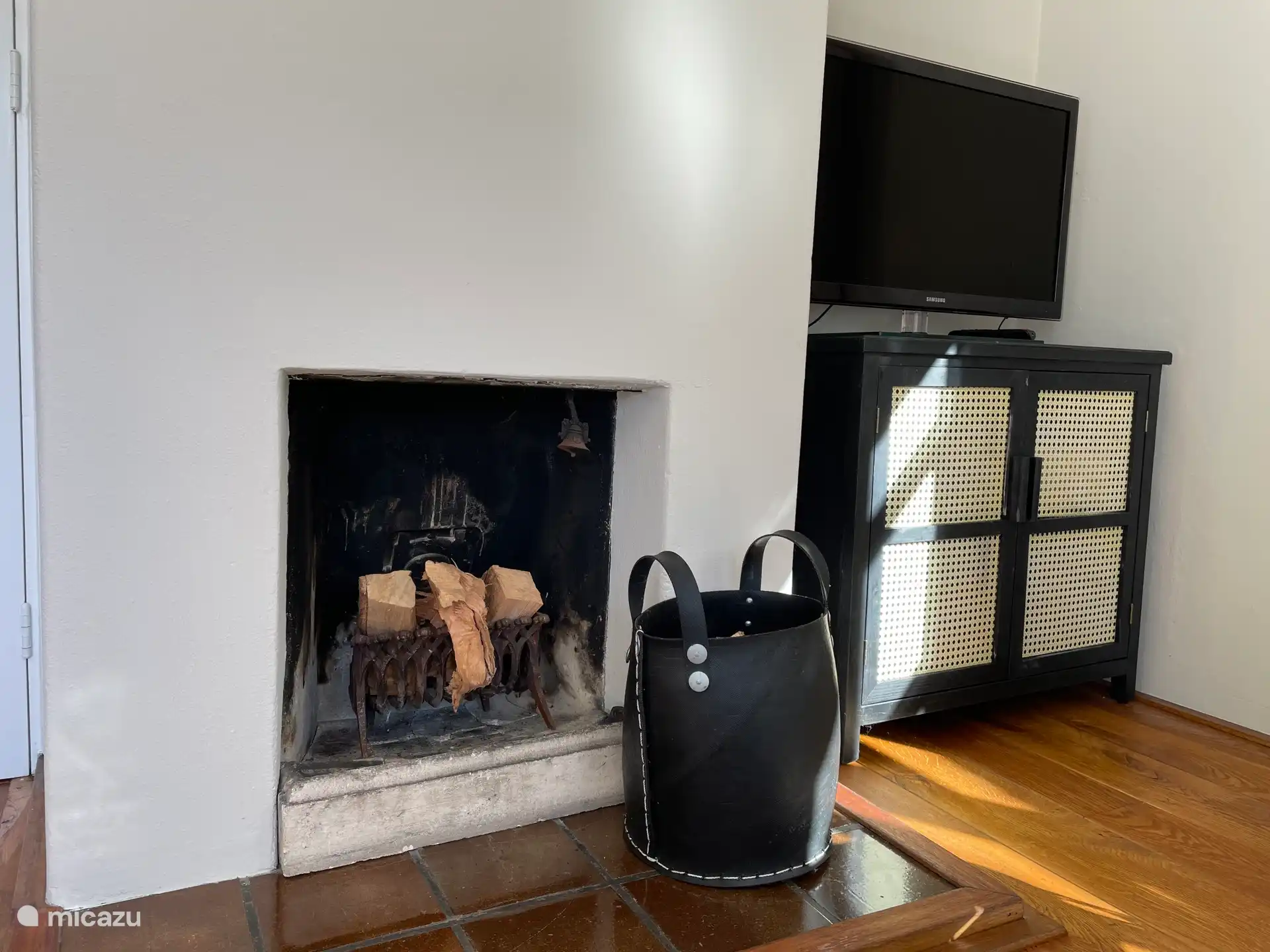 Helles Wohnzimmer, ausgestattet mit Esstisch, Sitzecke, Fernseher und gemütlichem Kamin.