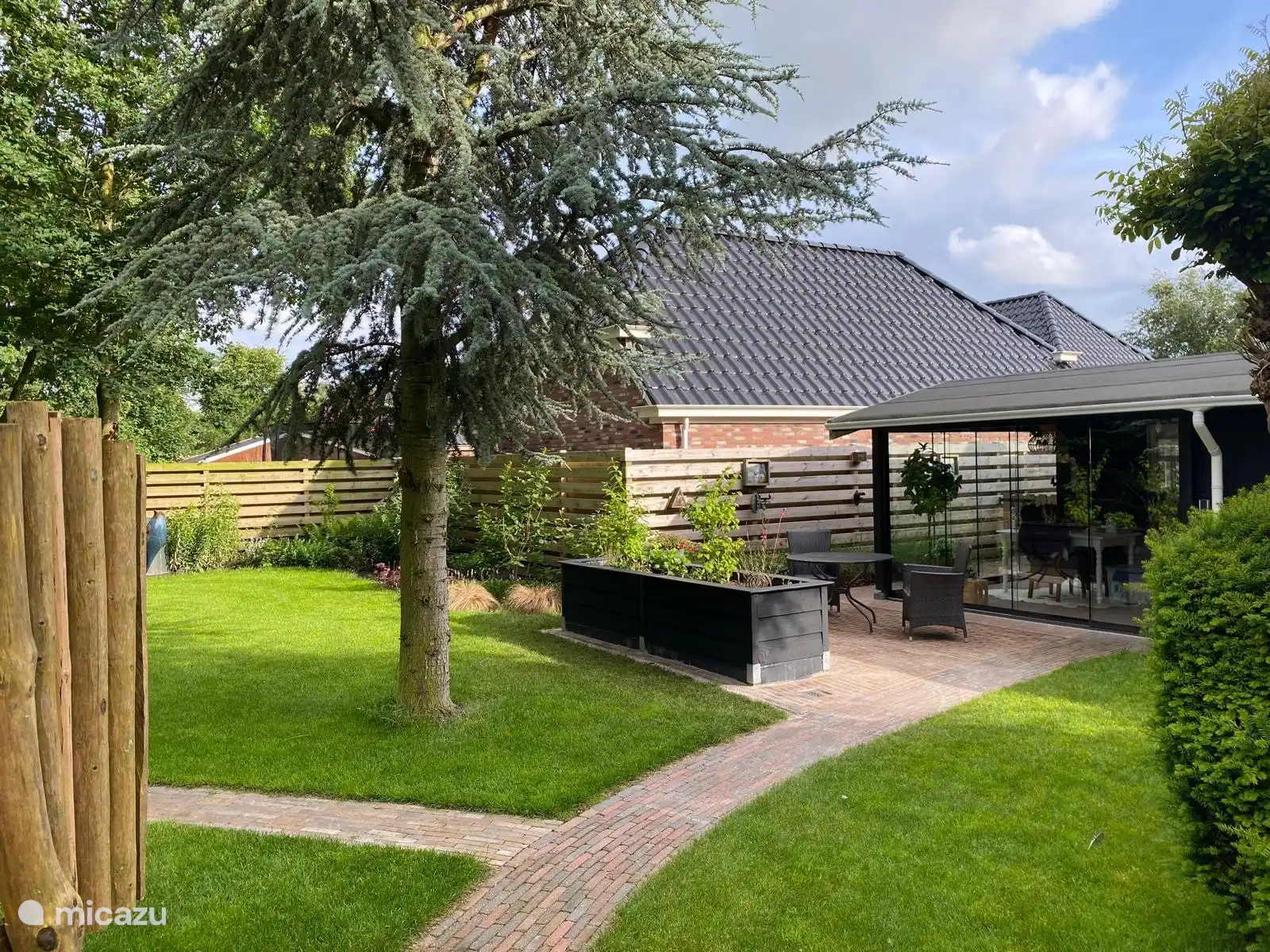 De ruime, gezellige tuinkamer voor het huisje is volledig van glas en voorzien van een terrasverwarmer. 