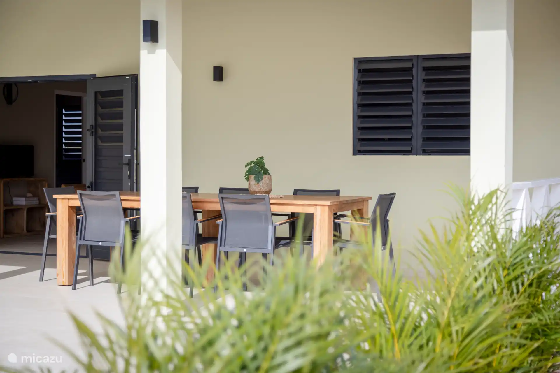 Véranda spacieuse avec grande table et 8 chaises, très royale pour le déjeuner et le dîner.