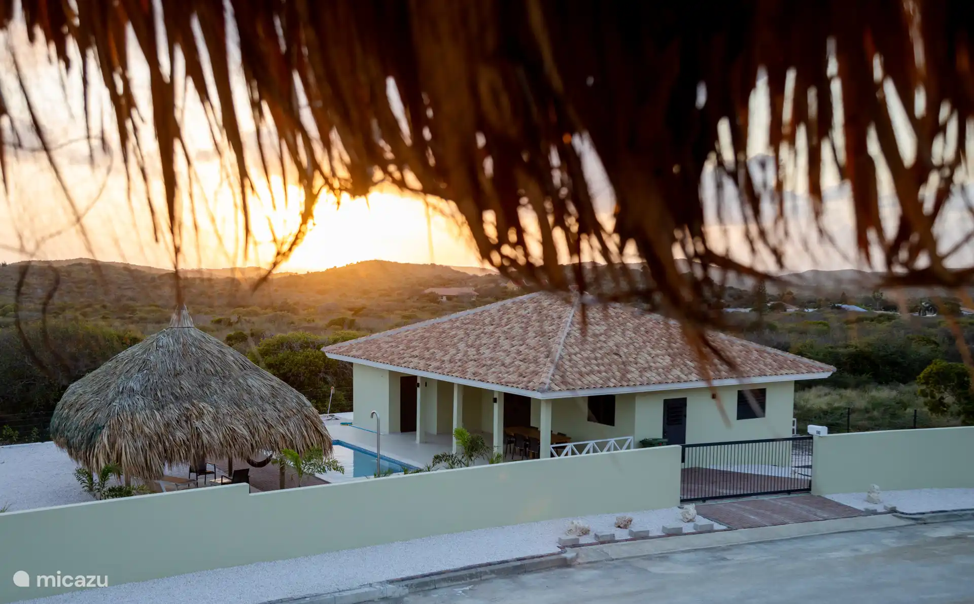 Villa et jardin avec un soleil couchant vu d’en haut.