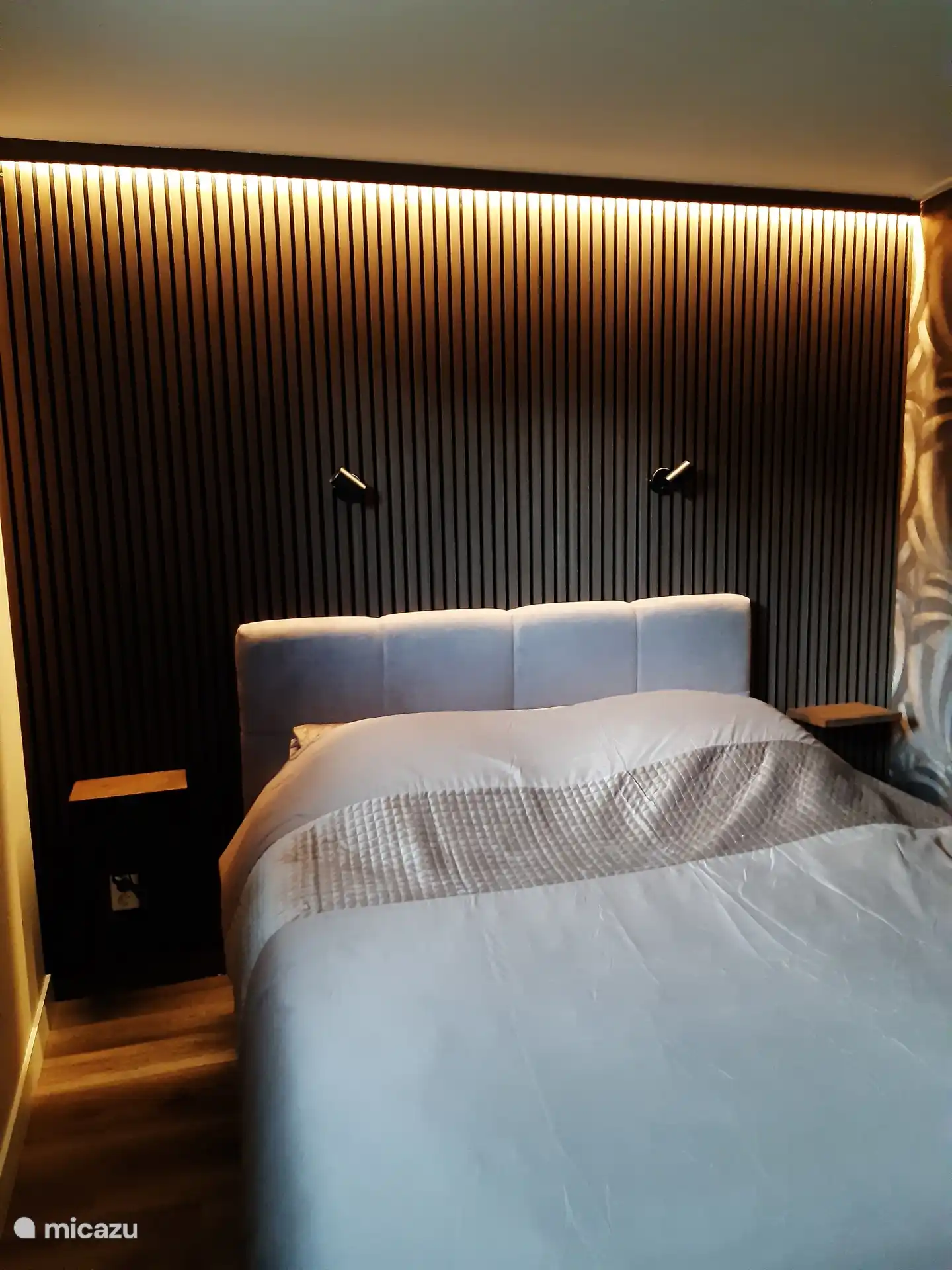 Slaapkamer met 2 persoons boxspring. Boven het bed bevindt zich indirecte sfeerverlichting. 