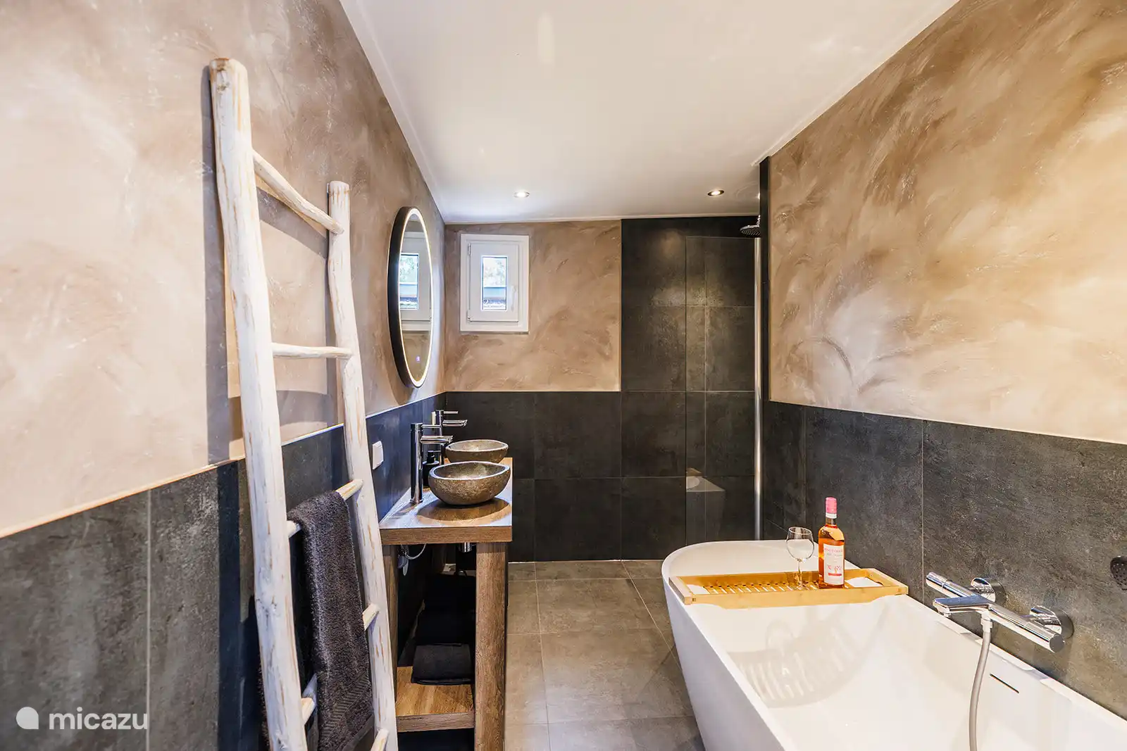 Luxe badkamer met vrijstaand ligbad,  dubbele wastafel en spiegel met verlichting én verwarming. 