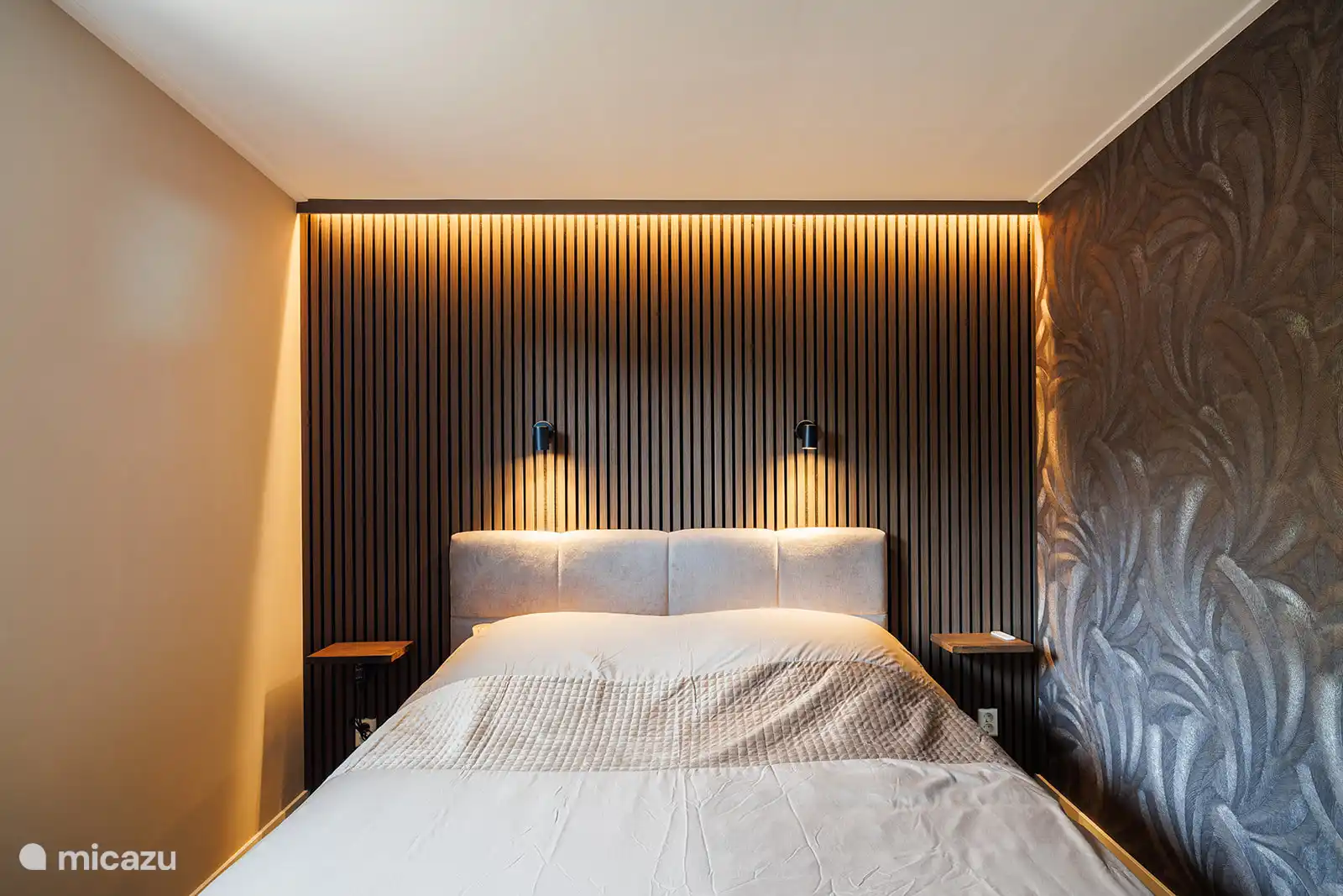 1e slaapkamer met 2-persoons boxspring, sfeerverlichting en leeslampjes boven het bed