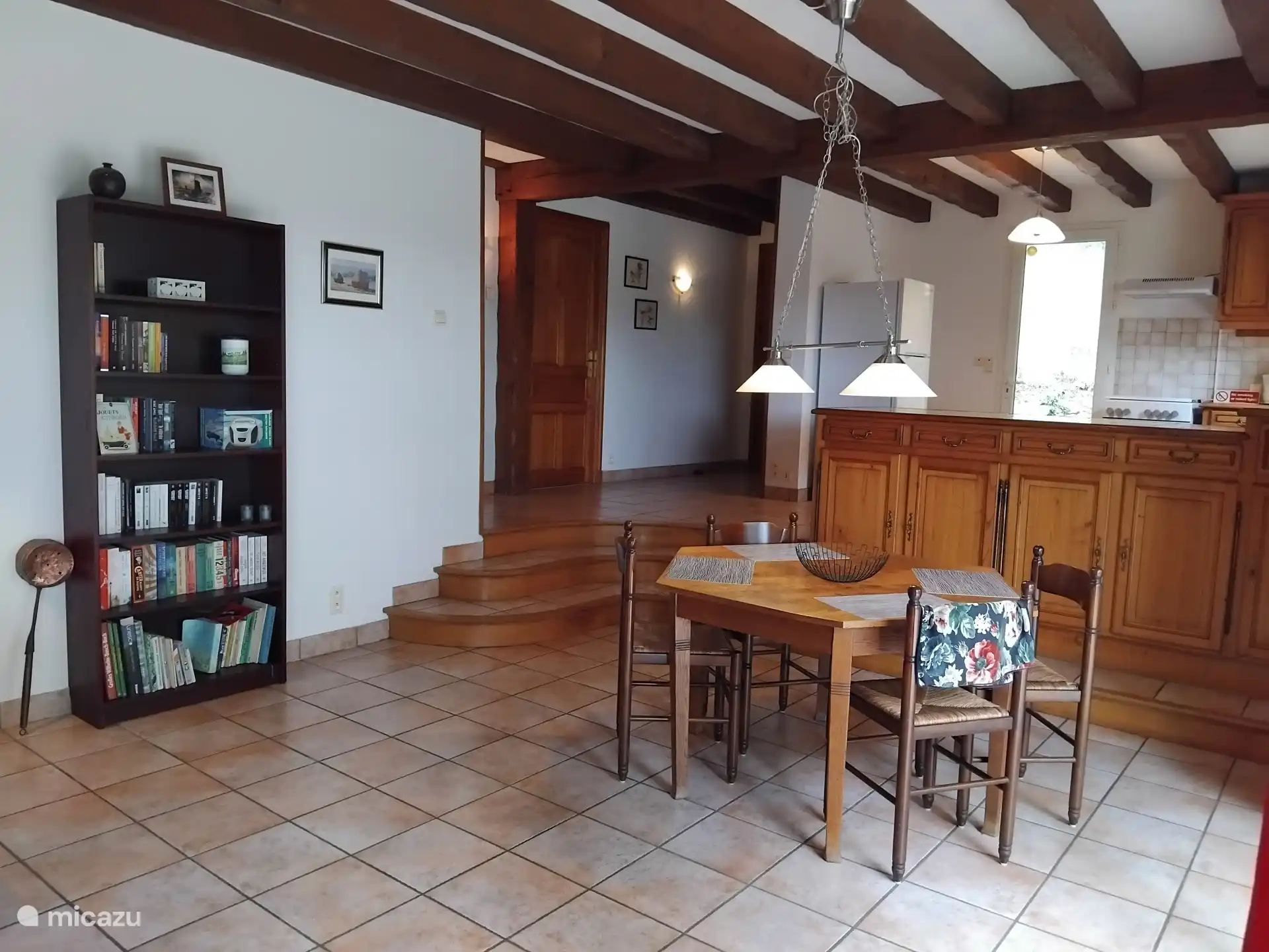 Salón con mesa de comedor y tres escalones hacia el pasillo y la cocina