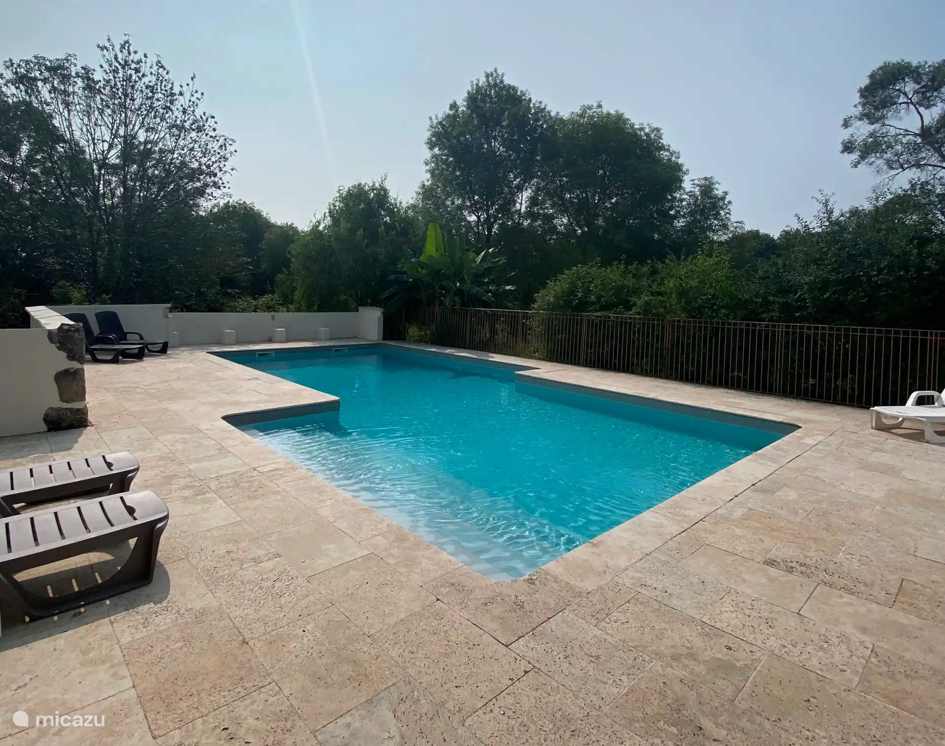 Private swimming pool with sun terrace, sun loungers, canopy and parasols.