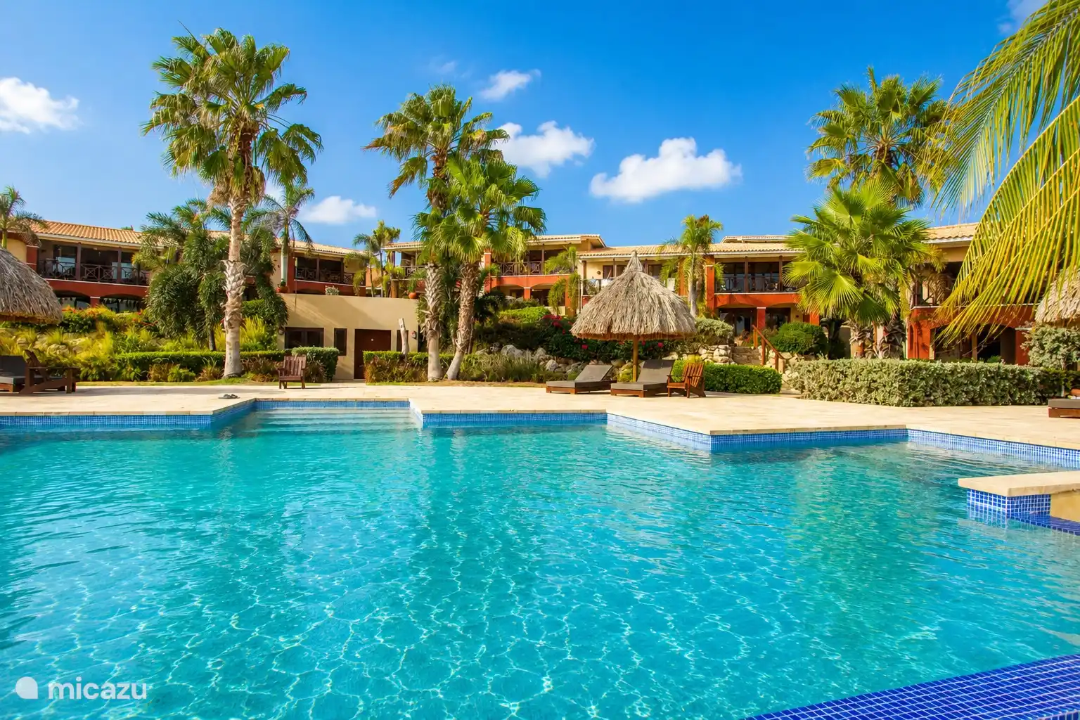 Communal swimming pool in a tropical setting, centrally located on the well-kept resort.