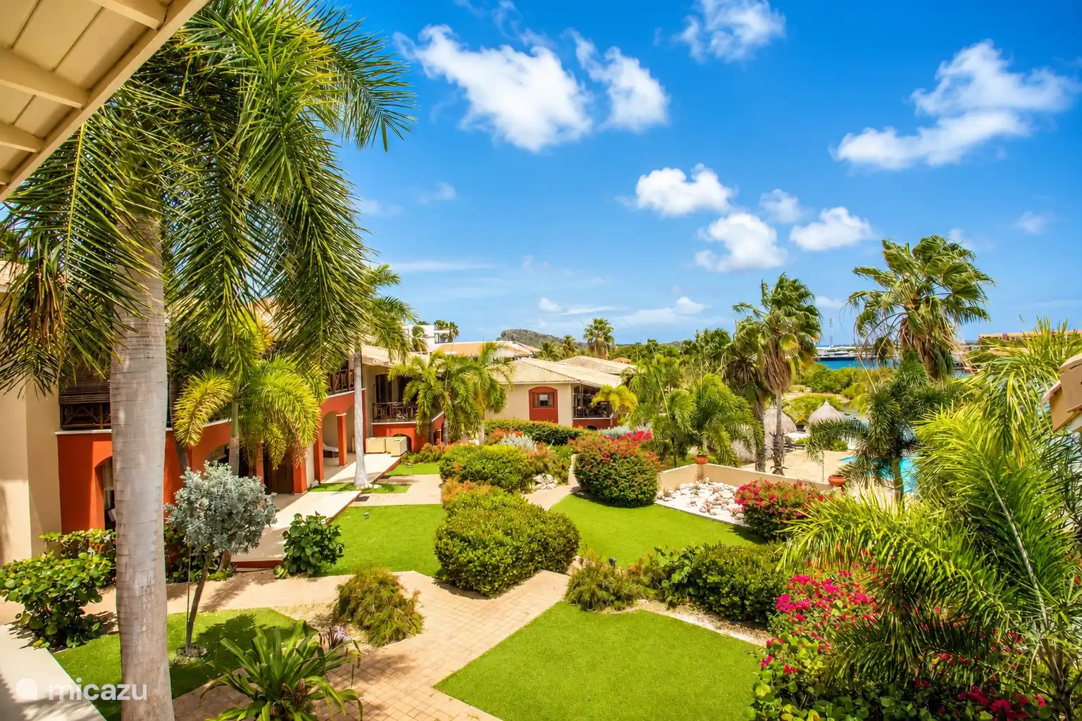 View over the tropical garden of the resort with palms, colorful plants and the swimming pool.