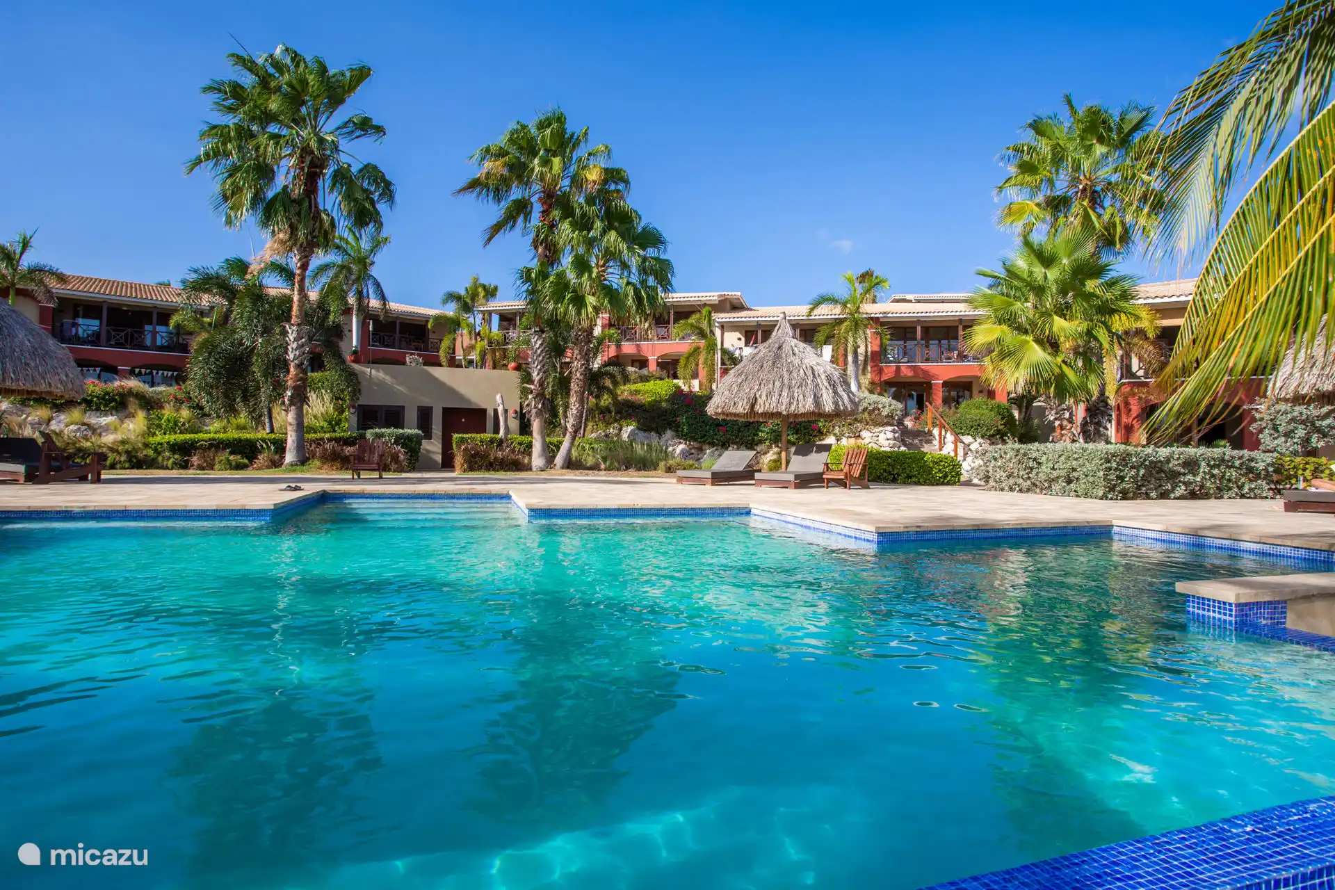 Gemeinschaftsschwimmbad in tropischer Umgebung, zentral auf dem gepflegten Resort gelegen.