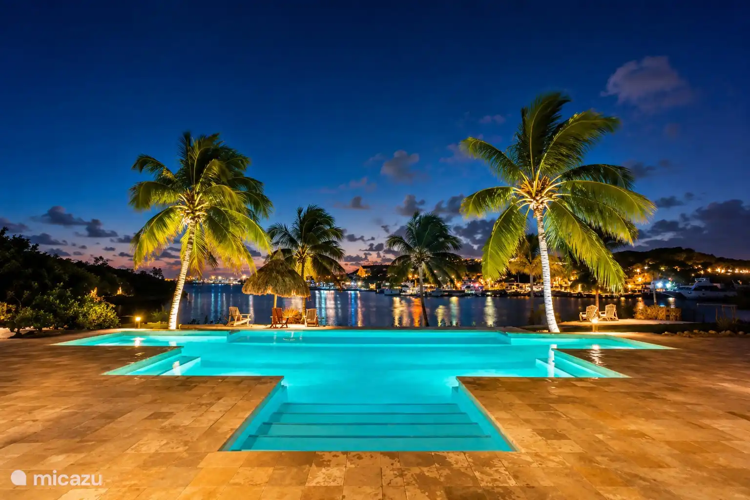 Attractively lit swimming pool in the evening, with a view of palms and the Spanish Water.