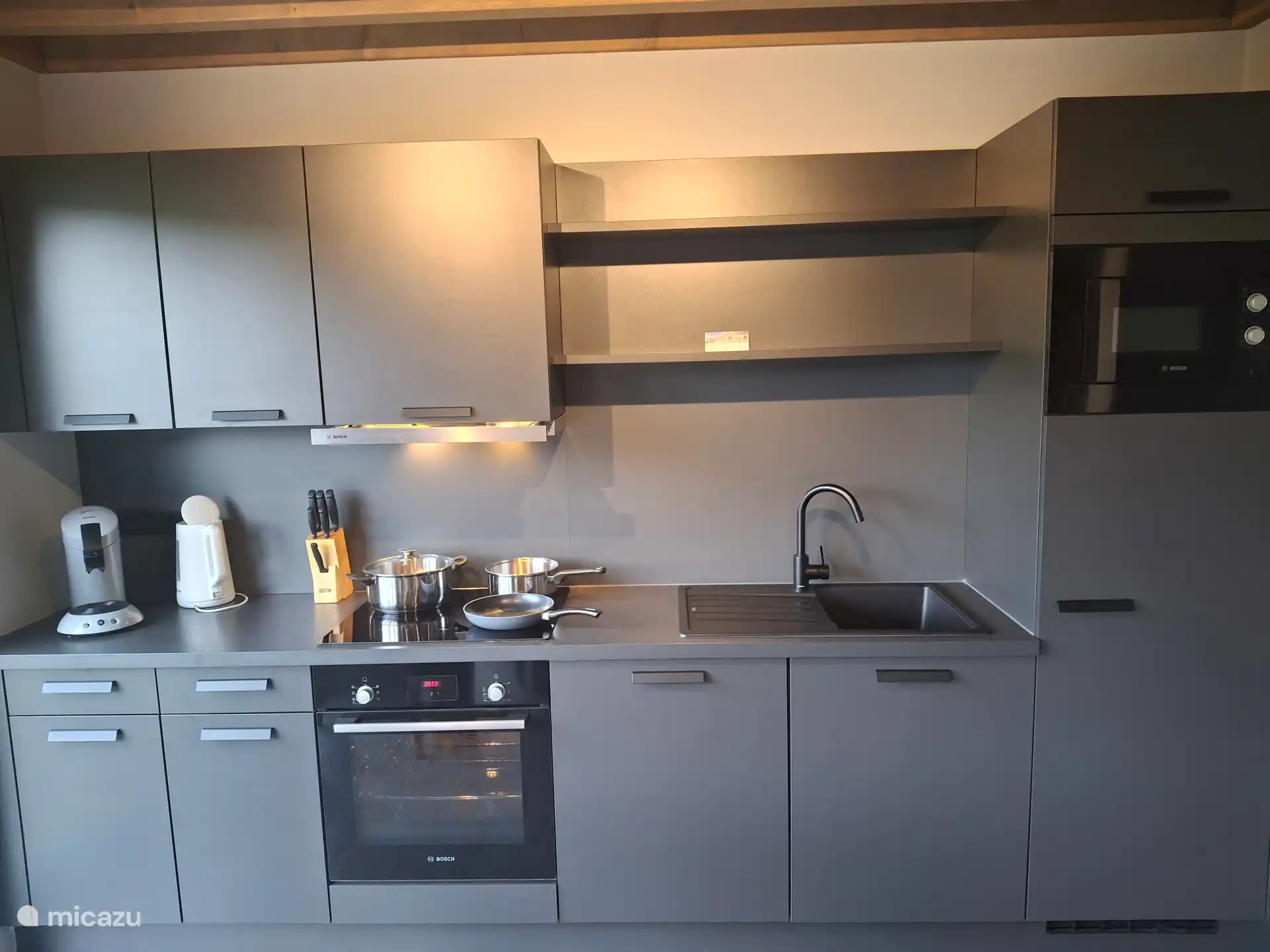 Voll ausgestattete Küche mit Ofen, Induktionsherd, Mikrowelle, Kühlschrank mit Gefrierfach und allen Küchengeräten