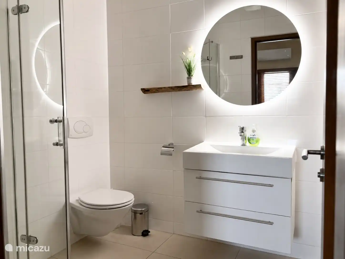 Badkamer met douche, toilet, wastafel en spiegel.