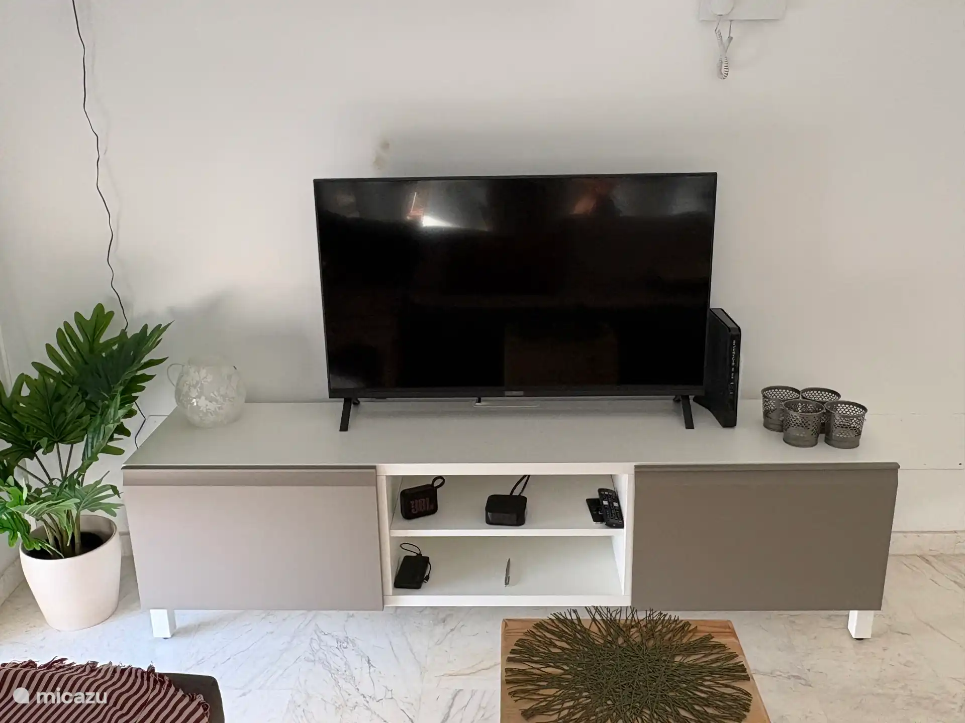 Grote smart TV op een handig meubel. In het linkerkastje liggen de gezelschapsspellen die uiteraard voor iedereen beschikbaar zijn