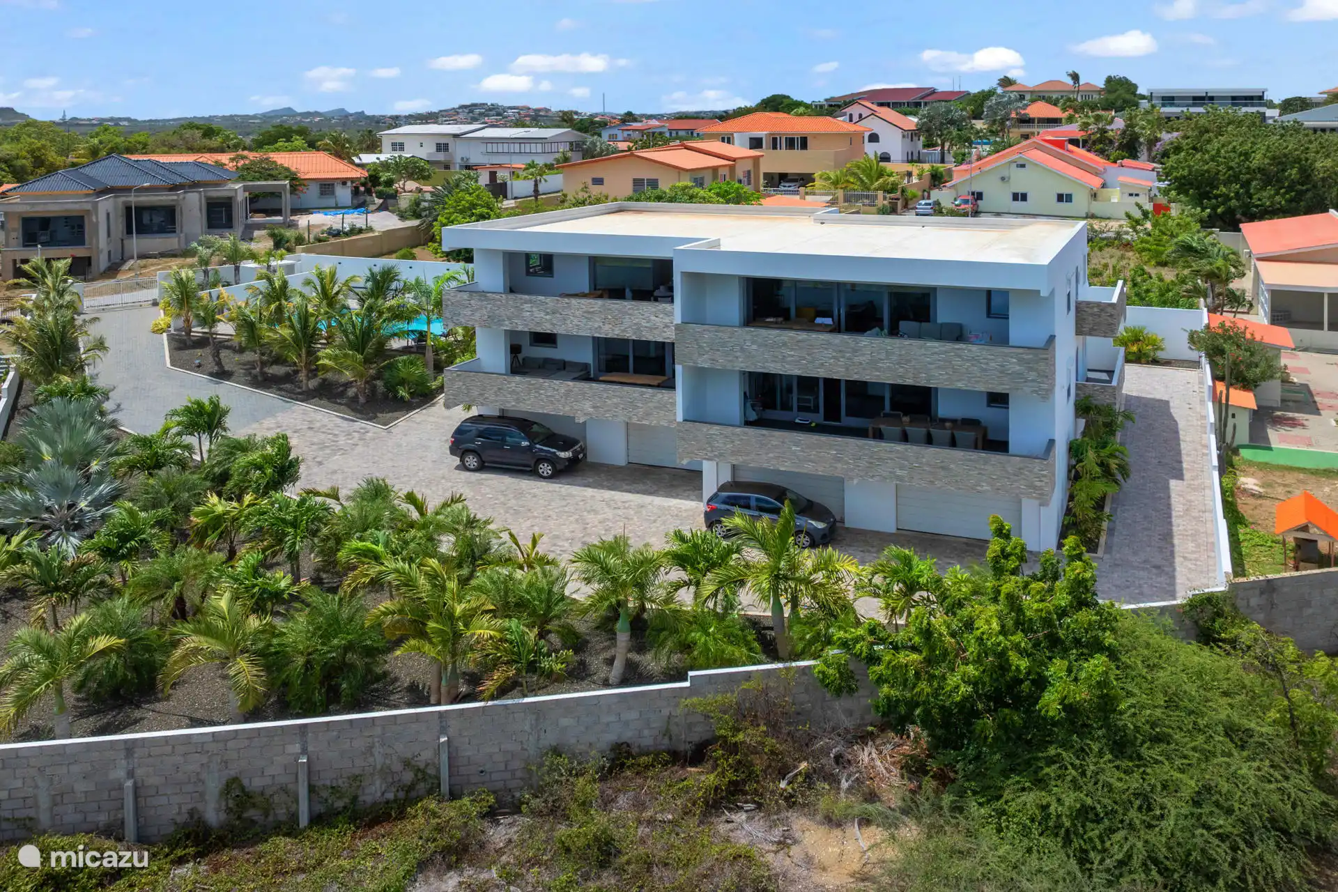 Buitenaanzicht, linksboven is onze accommodatie. Prive-garage, buiten parkeren ook mogelijk, palmbomen tuin