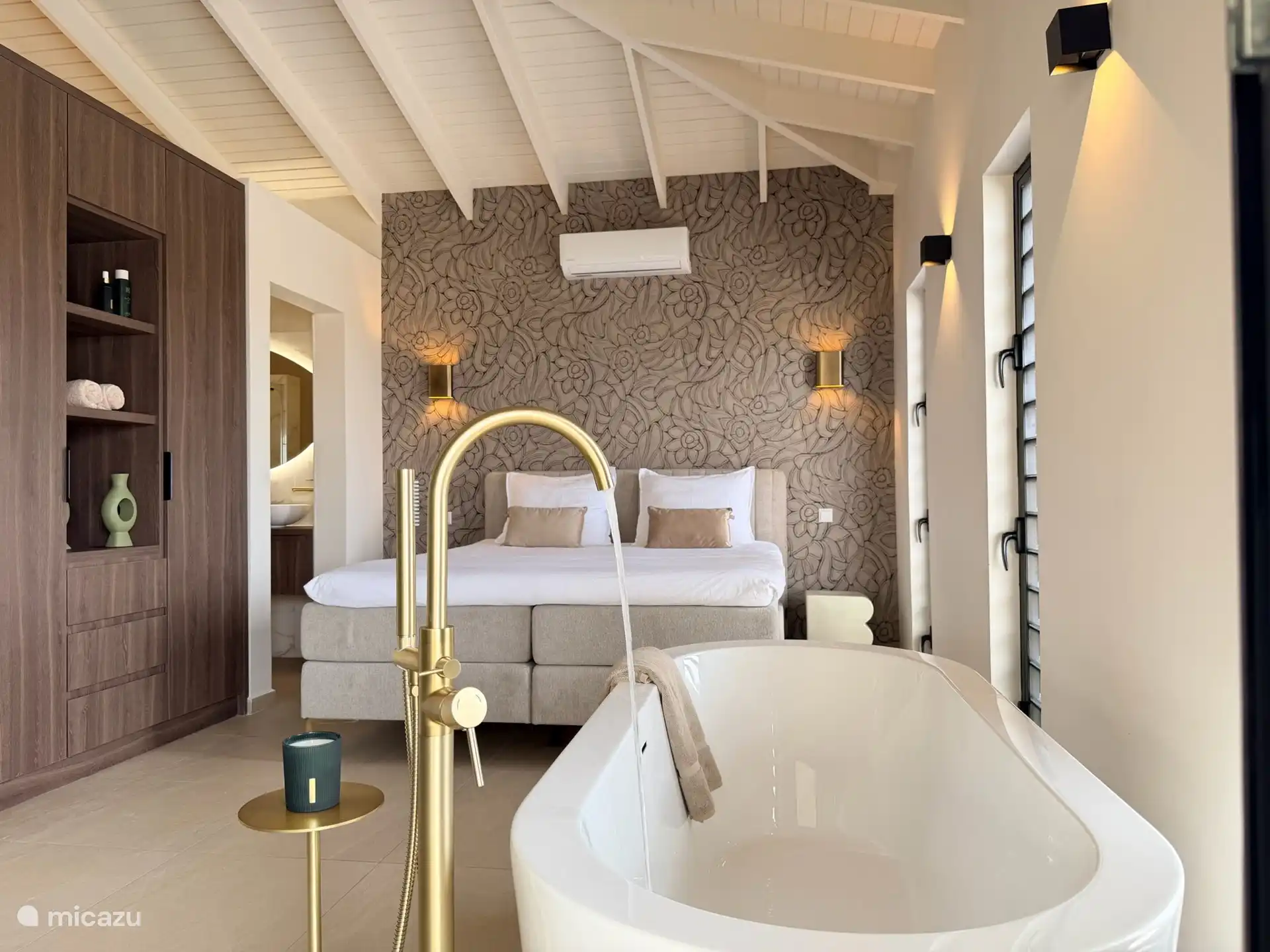 Vanuit het vrijstaande bad kijk je zo de ruime master suite in.