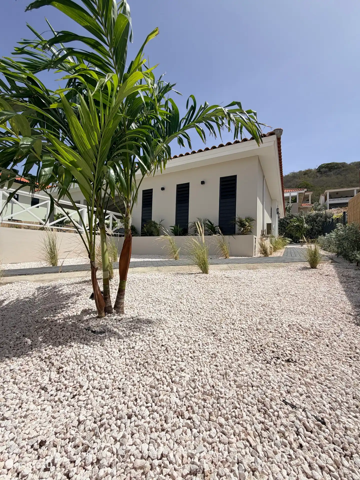 Tropisch groen rondom de villa zorgt voor een ontspannen en verzorgde sfeer. Via het vlakke pad langs de villa is de entree ook bereikbaar zonder gebruik te maken van de trap.