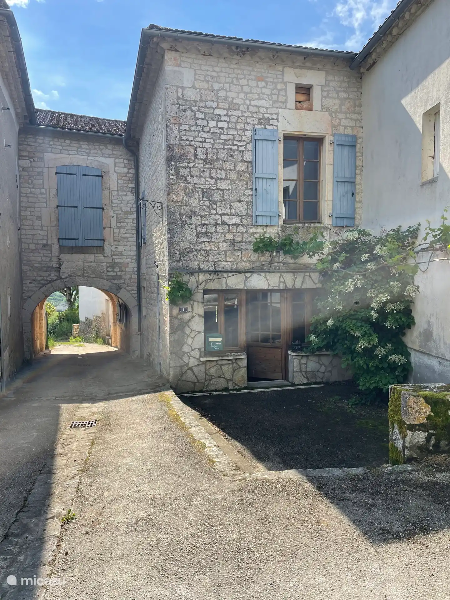 L’entrée de la maison. Façade adjacente à la place de l’église avec des places de parking. 