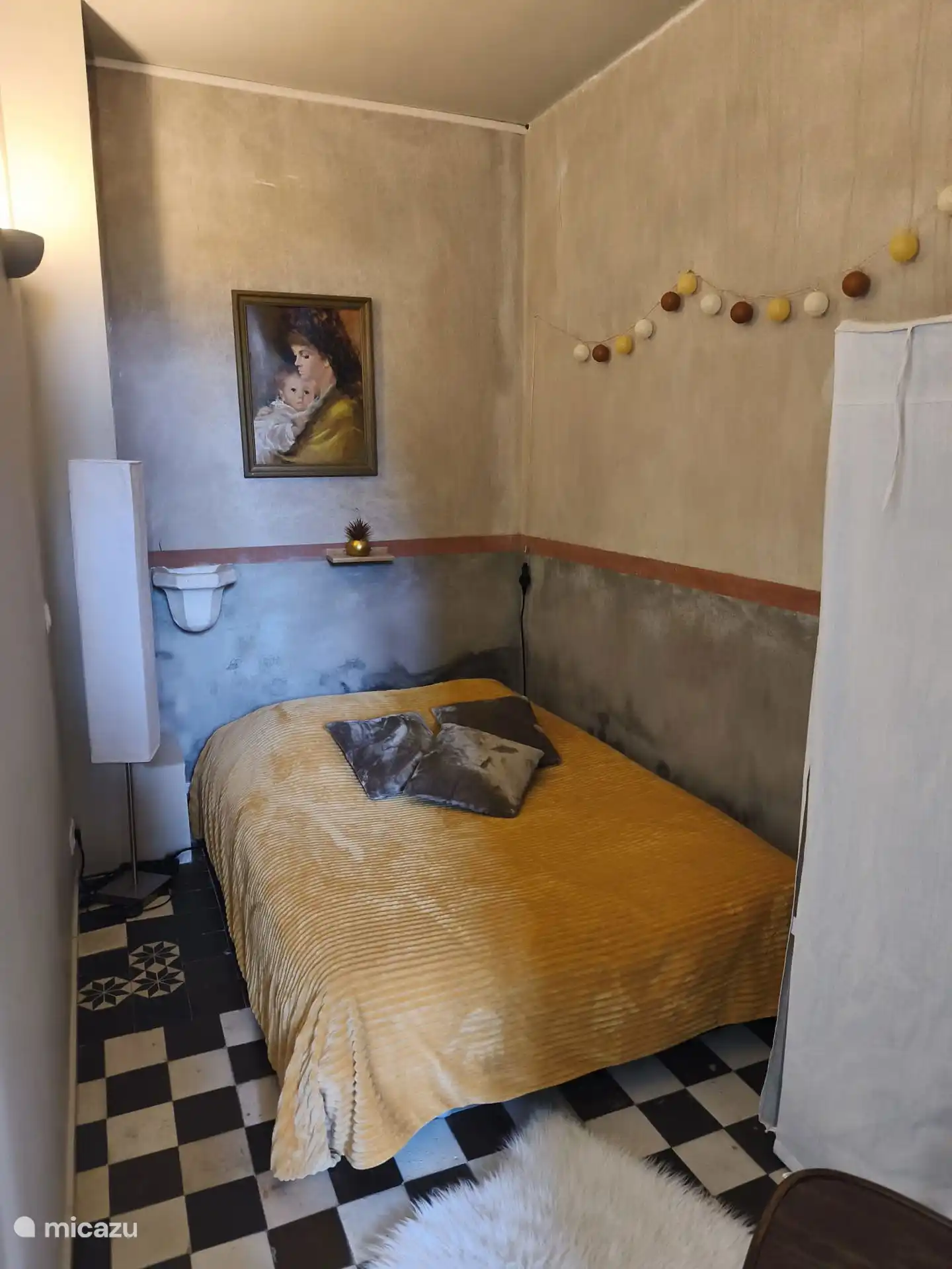 Ein kleines Schlafzimmer öffnet sich zum Hauptraum. Du hast einen Stuhl und einen Stoffschrank, um deine Sachen zu verstauen. Wandmontierte elektrische Heizung.