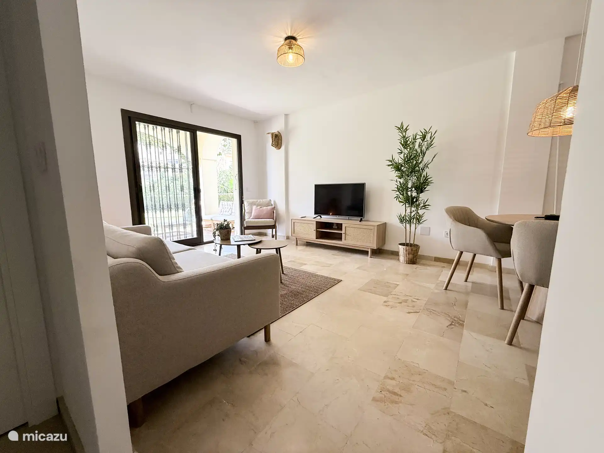 Woonkamer met televisie, airco en eettafel.