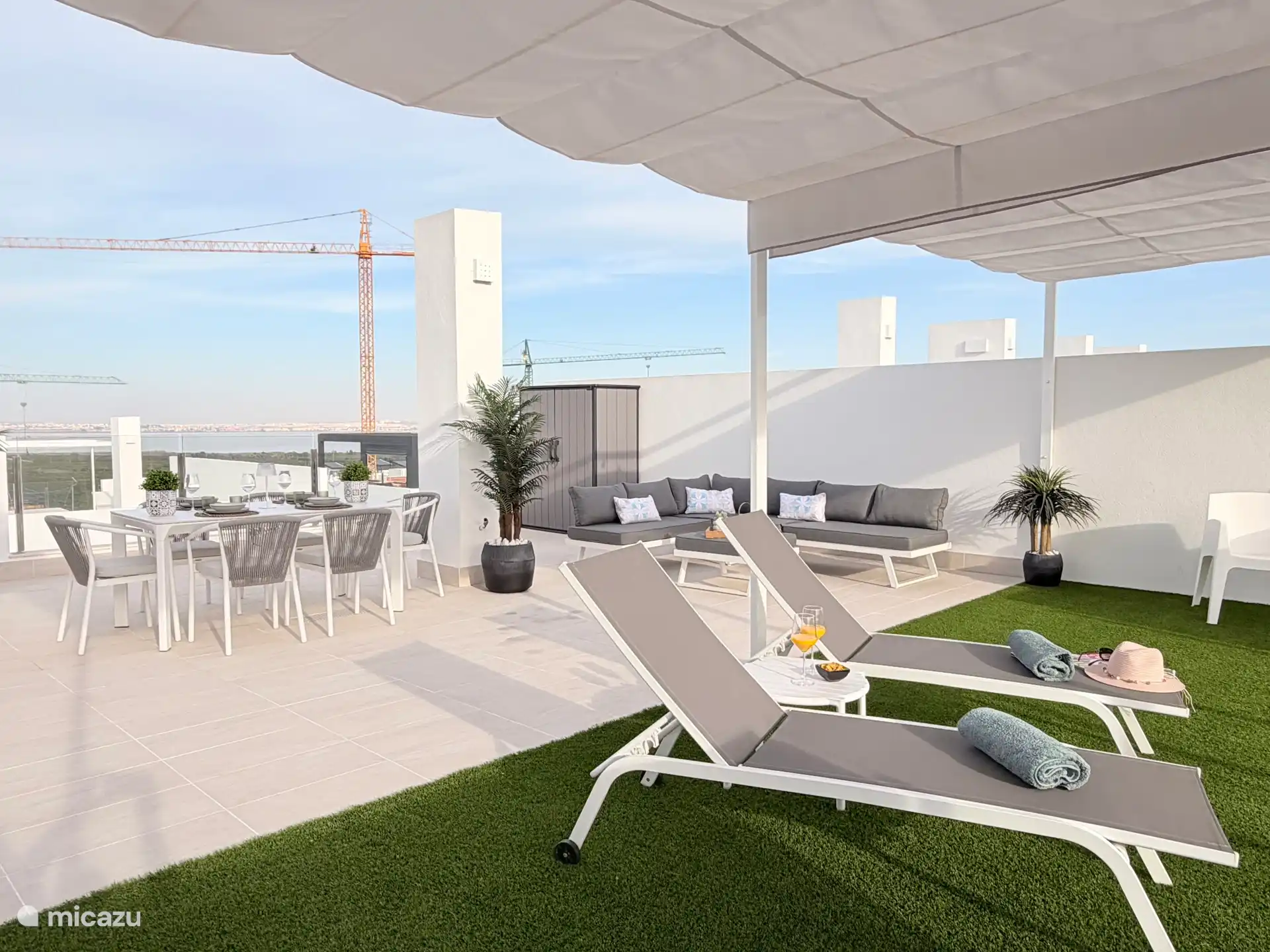 Royaal dakterras met tafel en stoelen,  loungebank en ligstoelen
