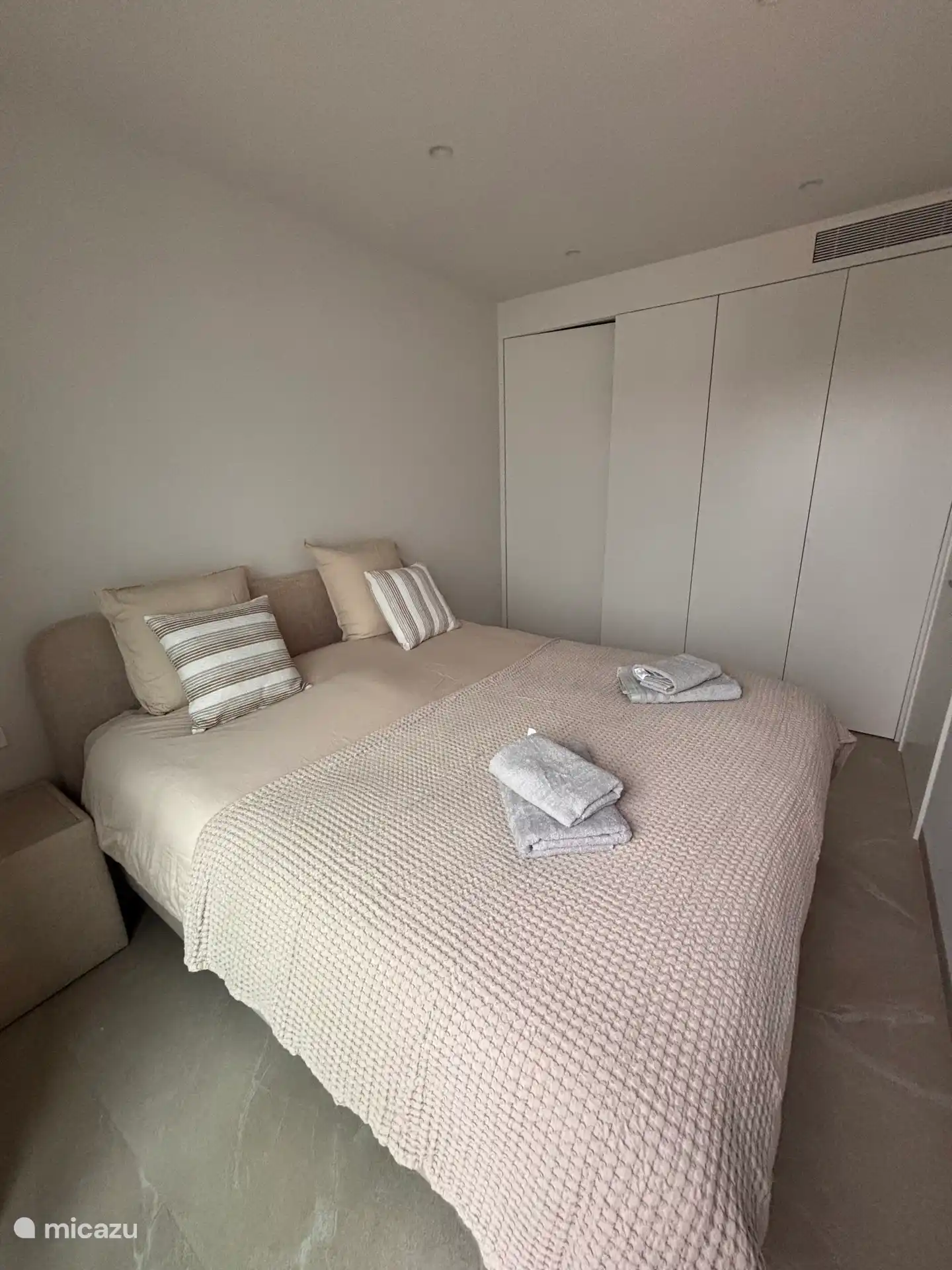 Dormitorio principal con cama matrimonial y armarios. Baño conectado con ducha, lavabo y inodoro. Hay un secador de pelo en el baño.