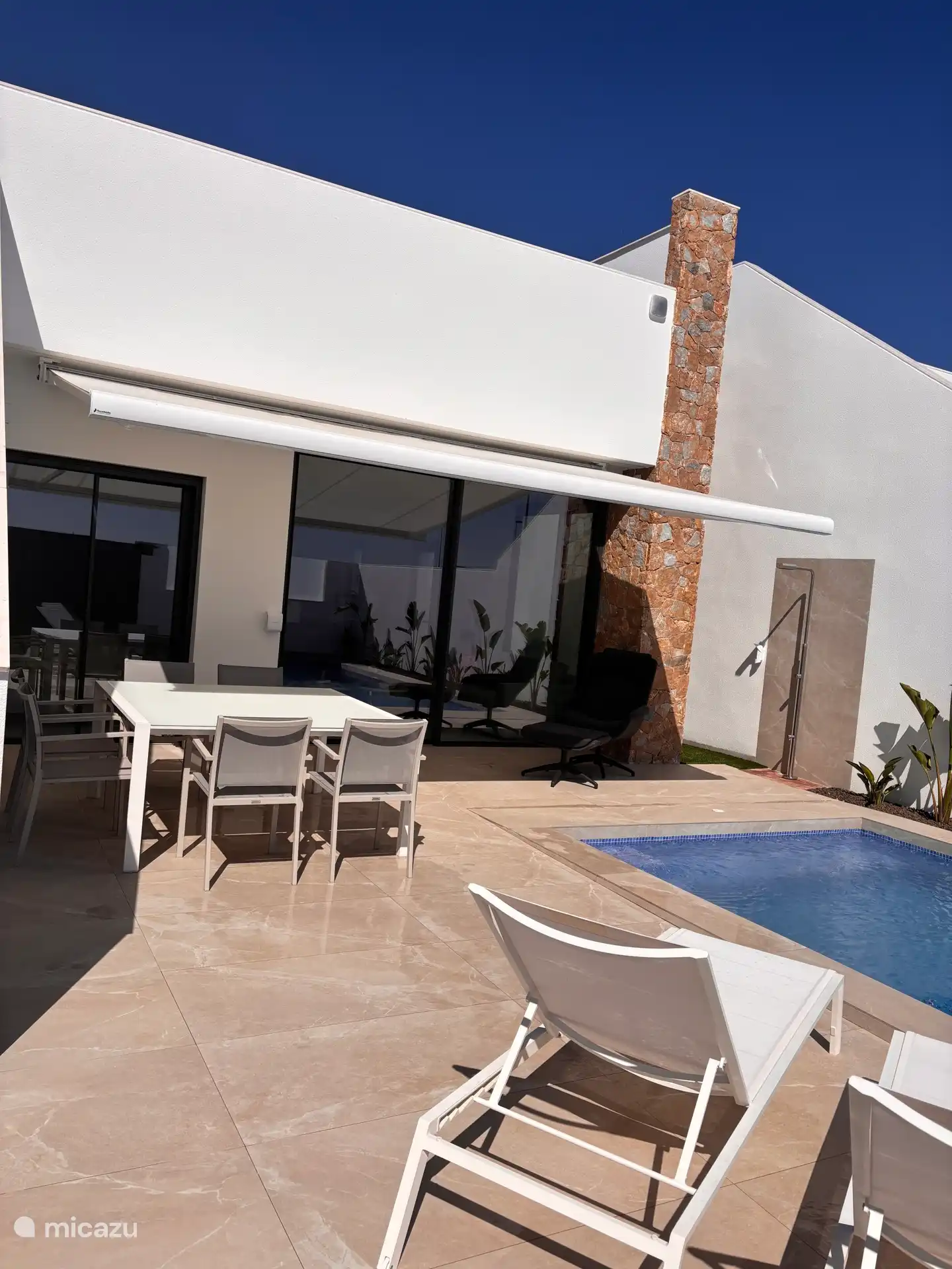 Terraza con tumbonas, mesa de comedor y sillas, y ducha exterior