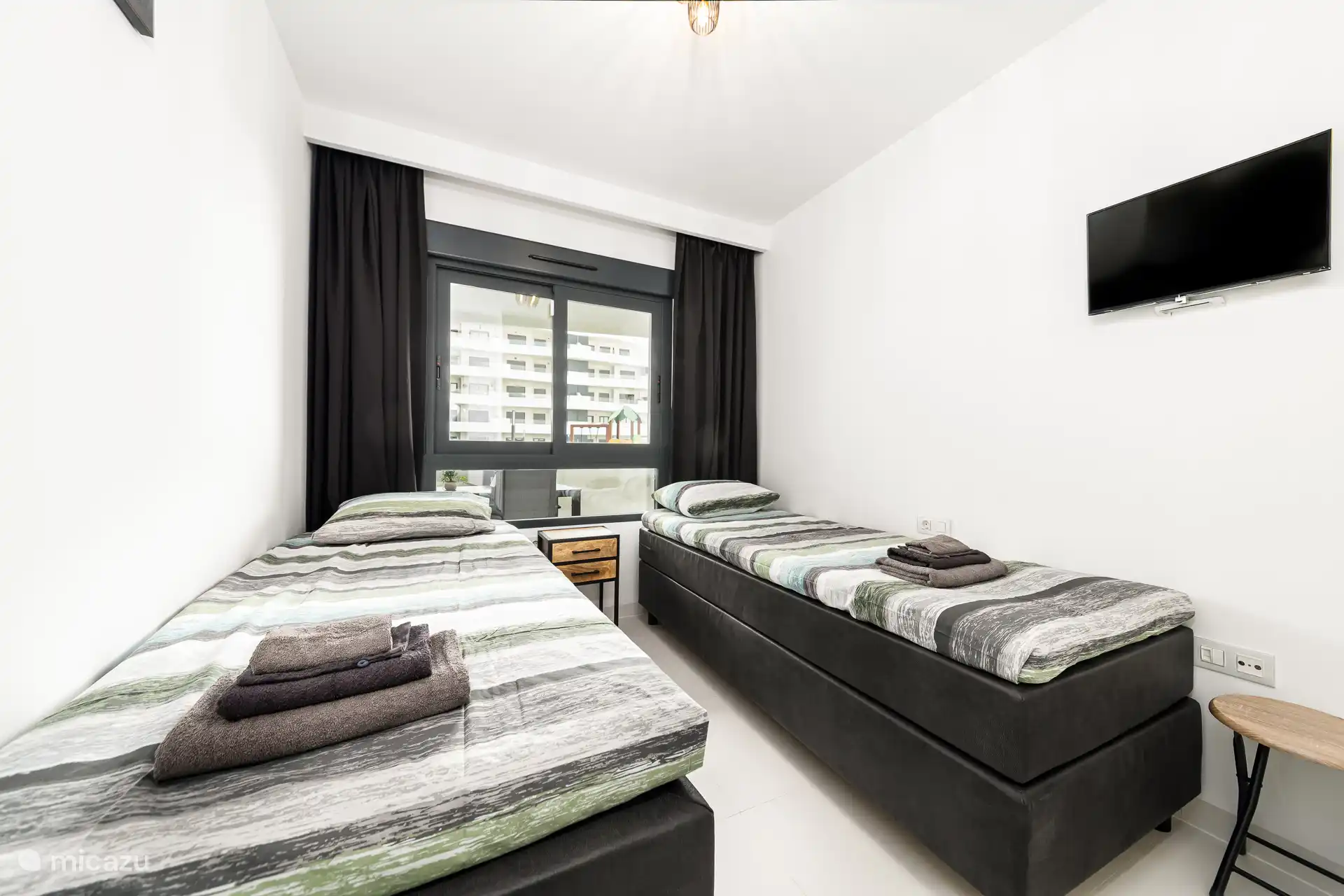 Kleine slaapkamer met twee één persoonsbedden (90 x 220) extra lang, inbouwkast en smart tv.