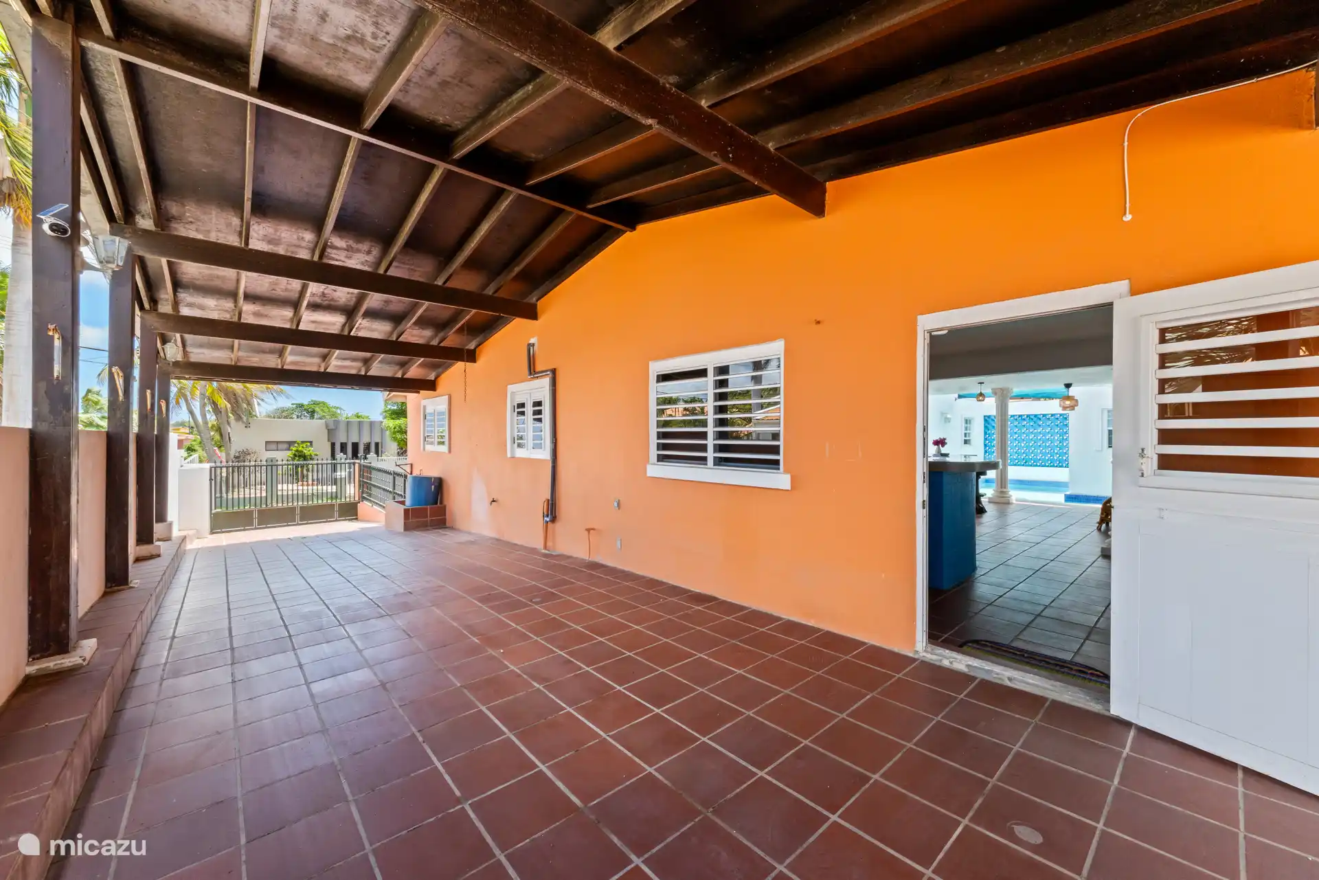 Extérieur de la villa avec zone couverte et terrasse.