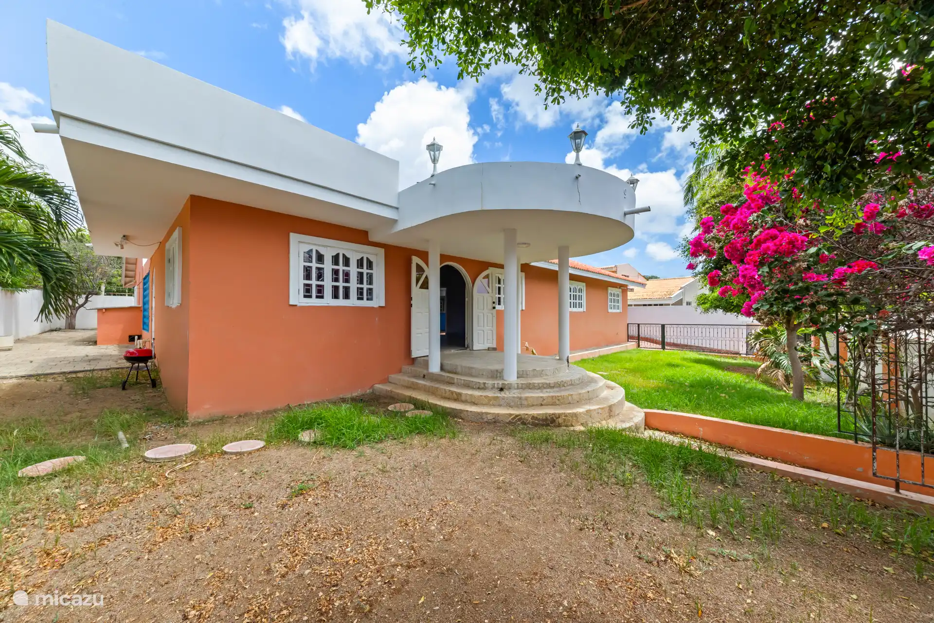 Vooraanzicht van Orange Lotus Villa met balkon en tropische tuin.