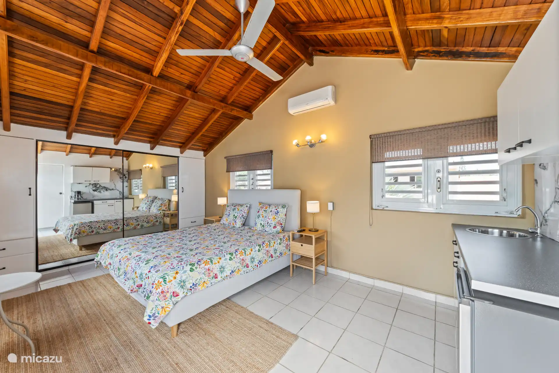 Chambre au rez-de-chaussée avec kitchenette et armoire miroir.