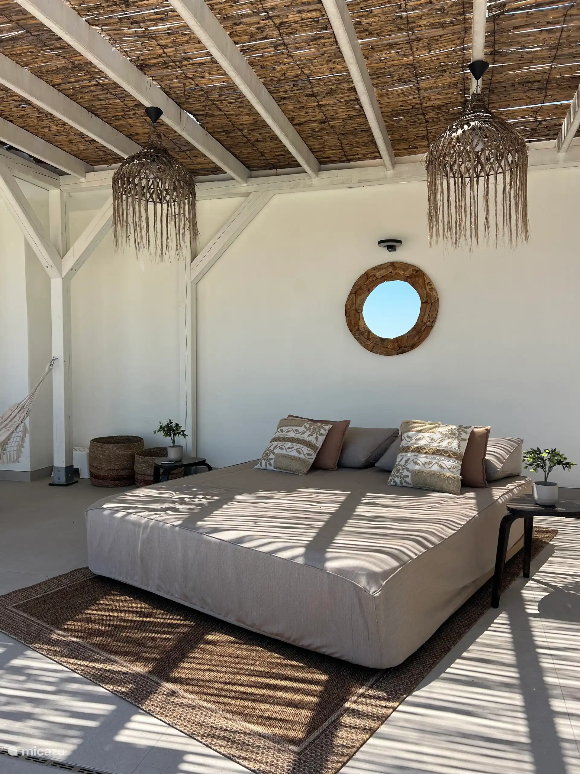 Un joli lit d’extérieur sous la pergola pour se détendre.