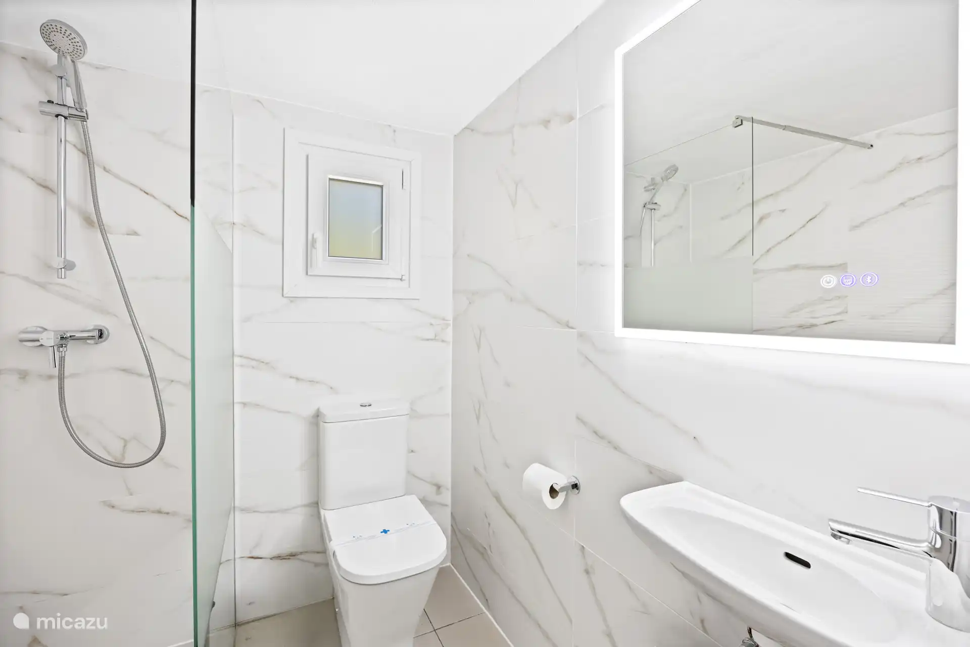 Luxe badkamer met marmeren wanden en inloopdouche – strak, modern en verzorgd tot in de details. Alsof je in een boutique hotel verblijft.