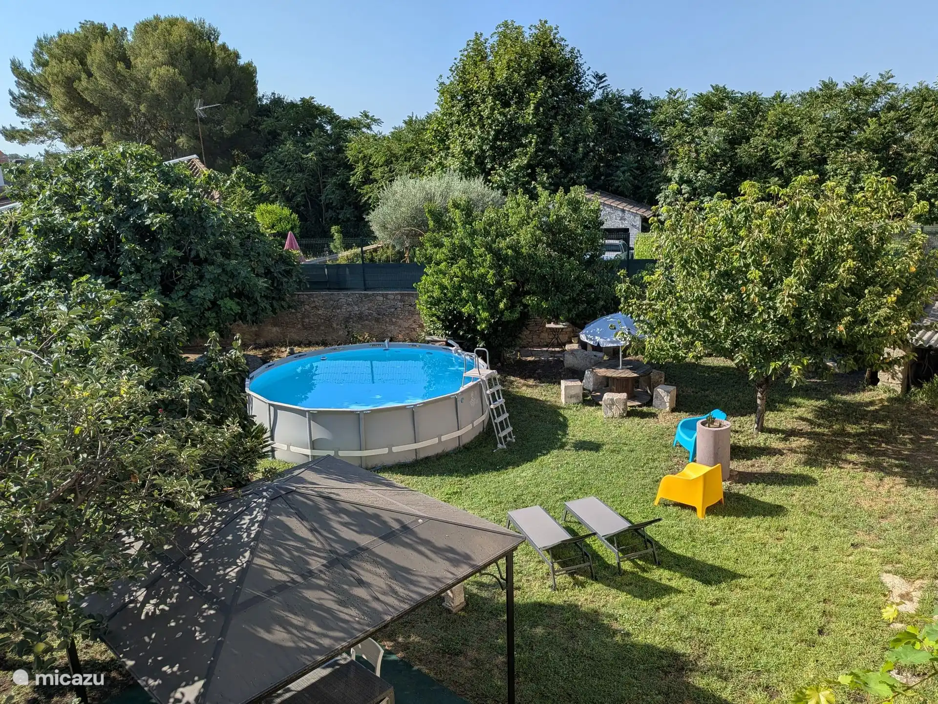 Omheinde tuin met zwembad en prieel