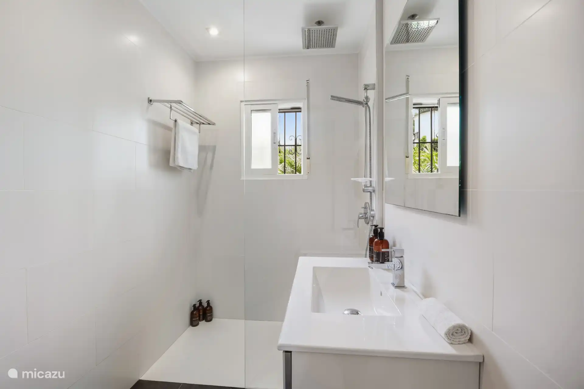 Salle de bain à l’étage avec douche à l’italienne et douche de pluie. Élégant, blanc et frais — exactement ce qu’il faut après une journée au soleil.
