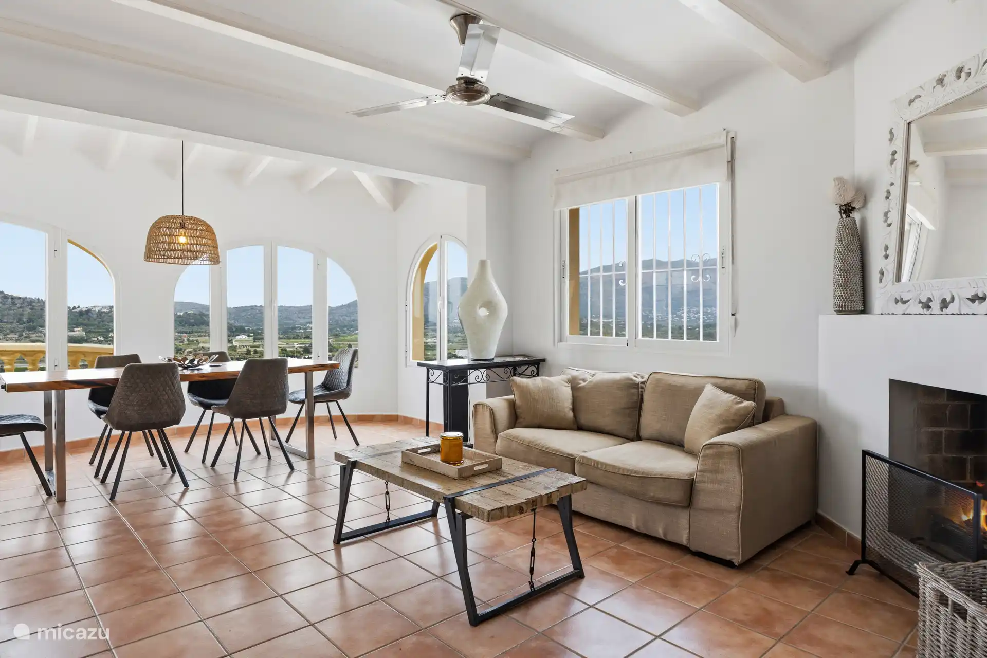 Espace salon dans l’appartement à l’étage avec cheminée, plafonds hauts et fenêtres cintrées donnant sur le Montgó. Léger et atmosphérique.