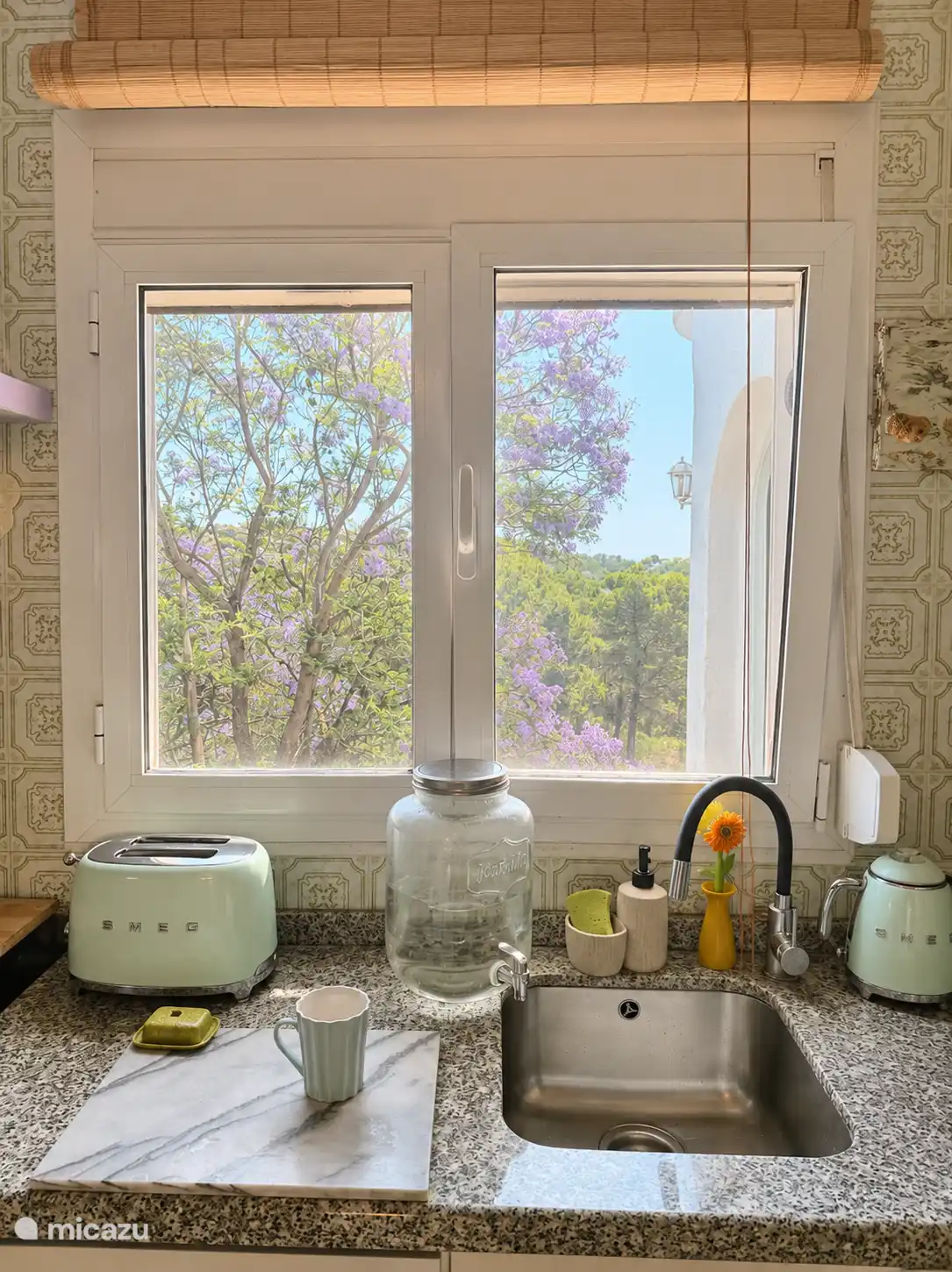 Die Küche von Casa Verda ist klein, gemütlich und voller Charakter. Vintage-Fliesen, spanische Holztüren und boho-Ibiza-Details schaffen eine warme Atmosphäre – ein Retro-Smeg-Kühlschrank. Und Küchenfenster mit Aussicht.