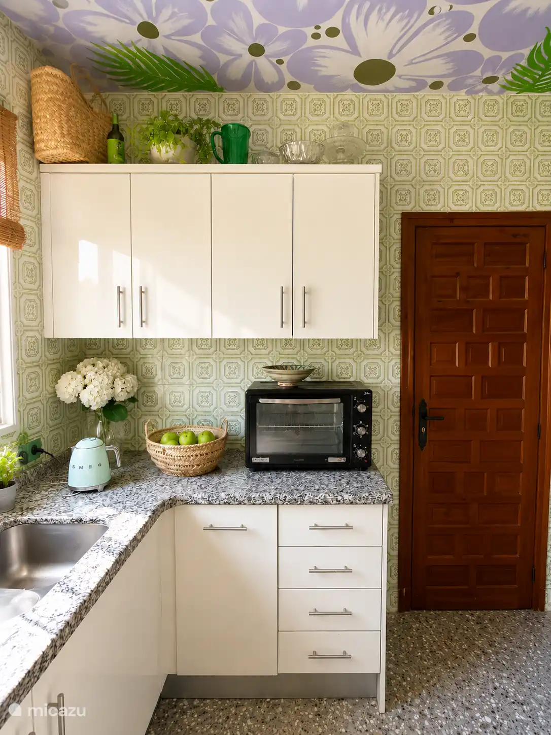 Die Küche von Casa Verda ist klein, gemütlich und voller Charakter. Vintage-Fliesen, spanische Holztüren und boho-Ibiza-Details schaffen eine warme Atmosphäre – ein Retro-Smeg-Kühlschrank. Und Küchenfenster mit Aussicht.